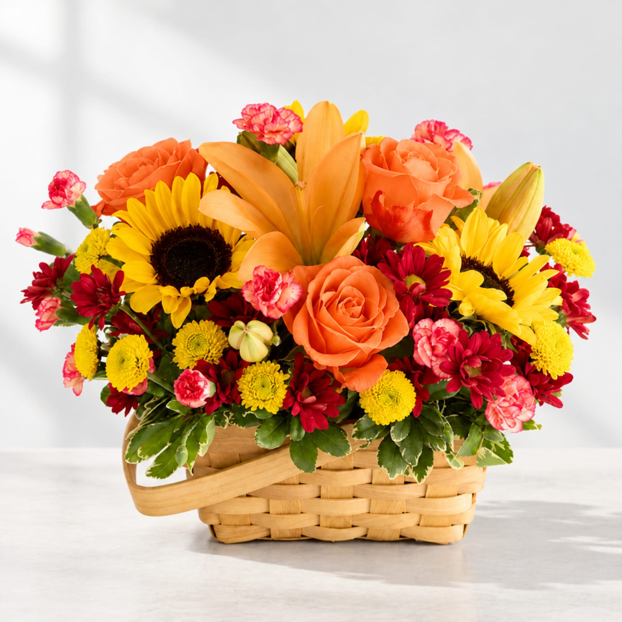 Basket arrangement with sunflowers, orange roses, and pink carnations