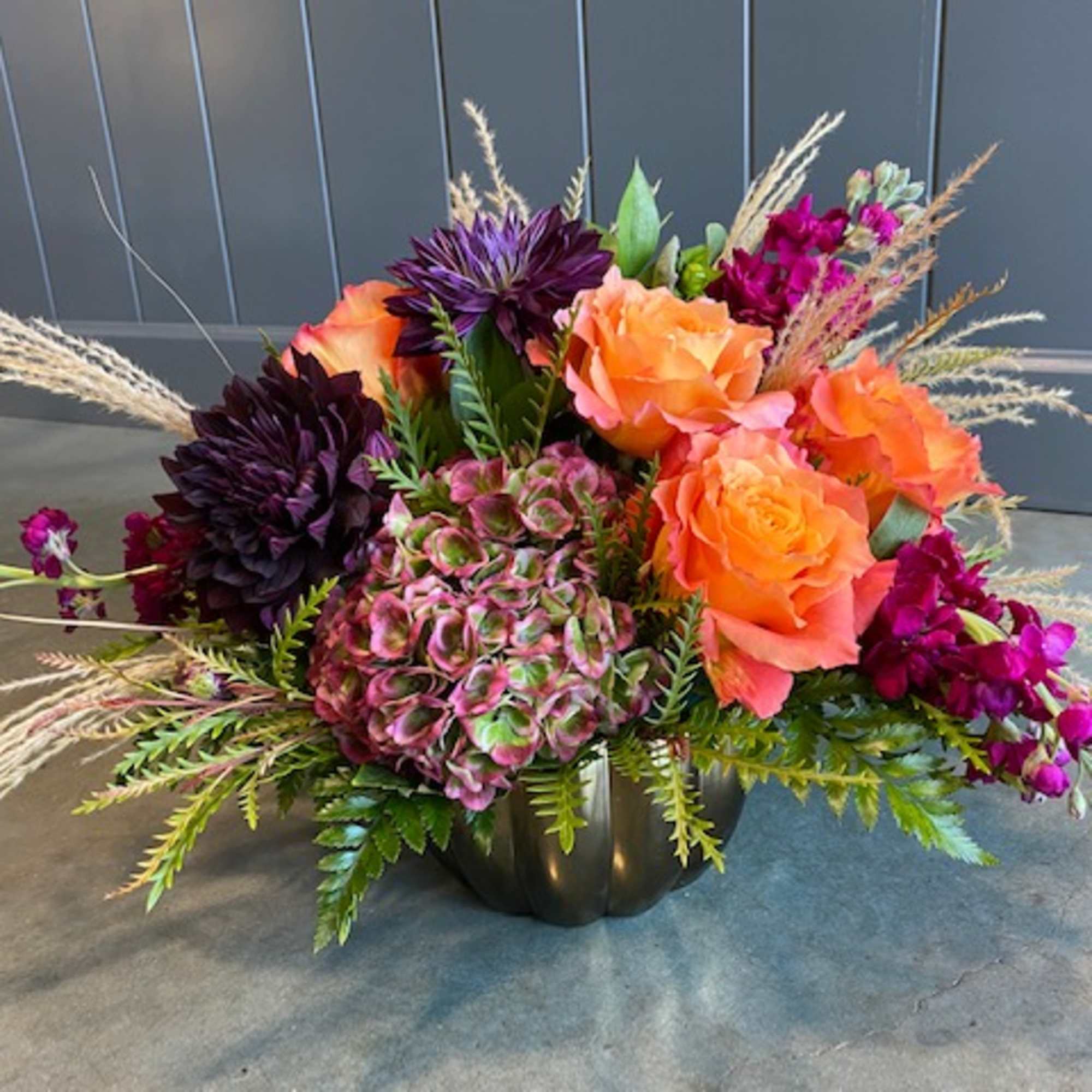 Orange and purple floral arrangement in a dark vase