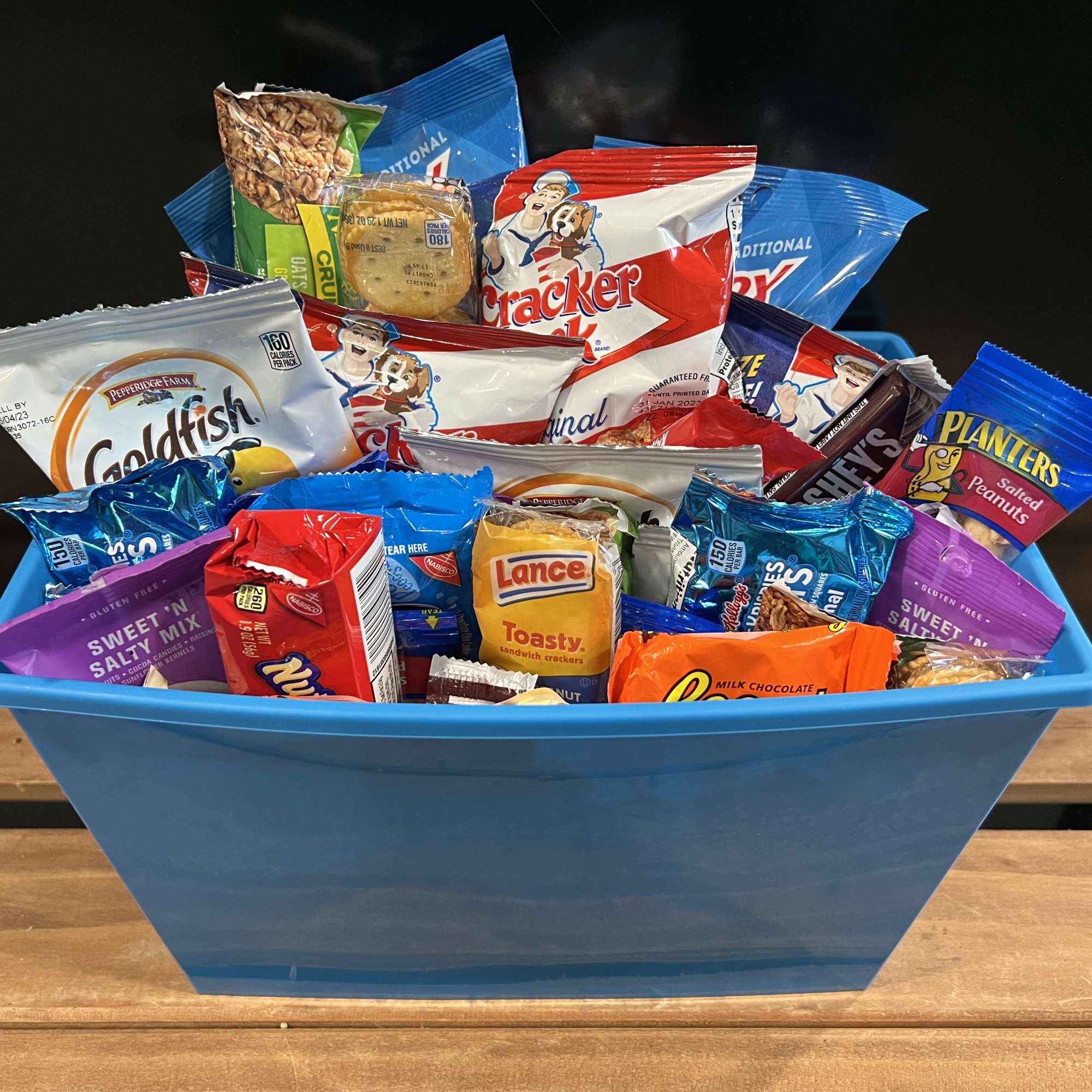 Blue basket filled with assorted snack packs and candy bars