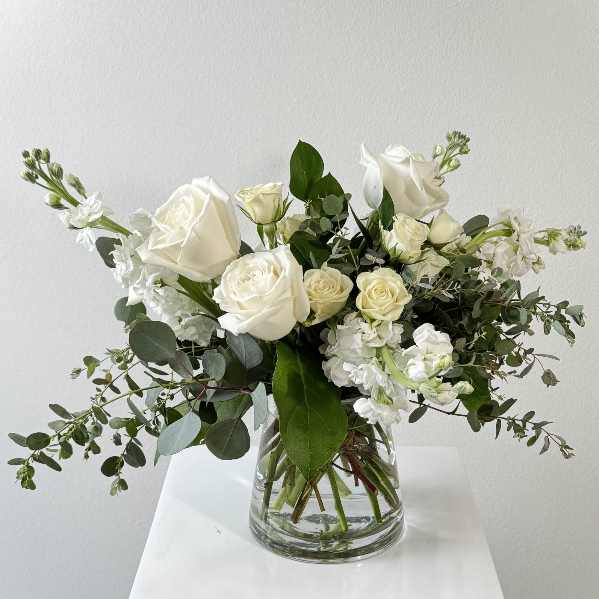 White roses and white stock in a clear glass vase