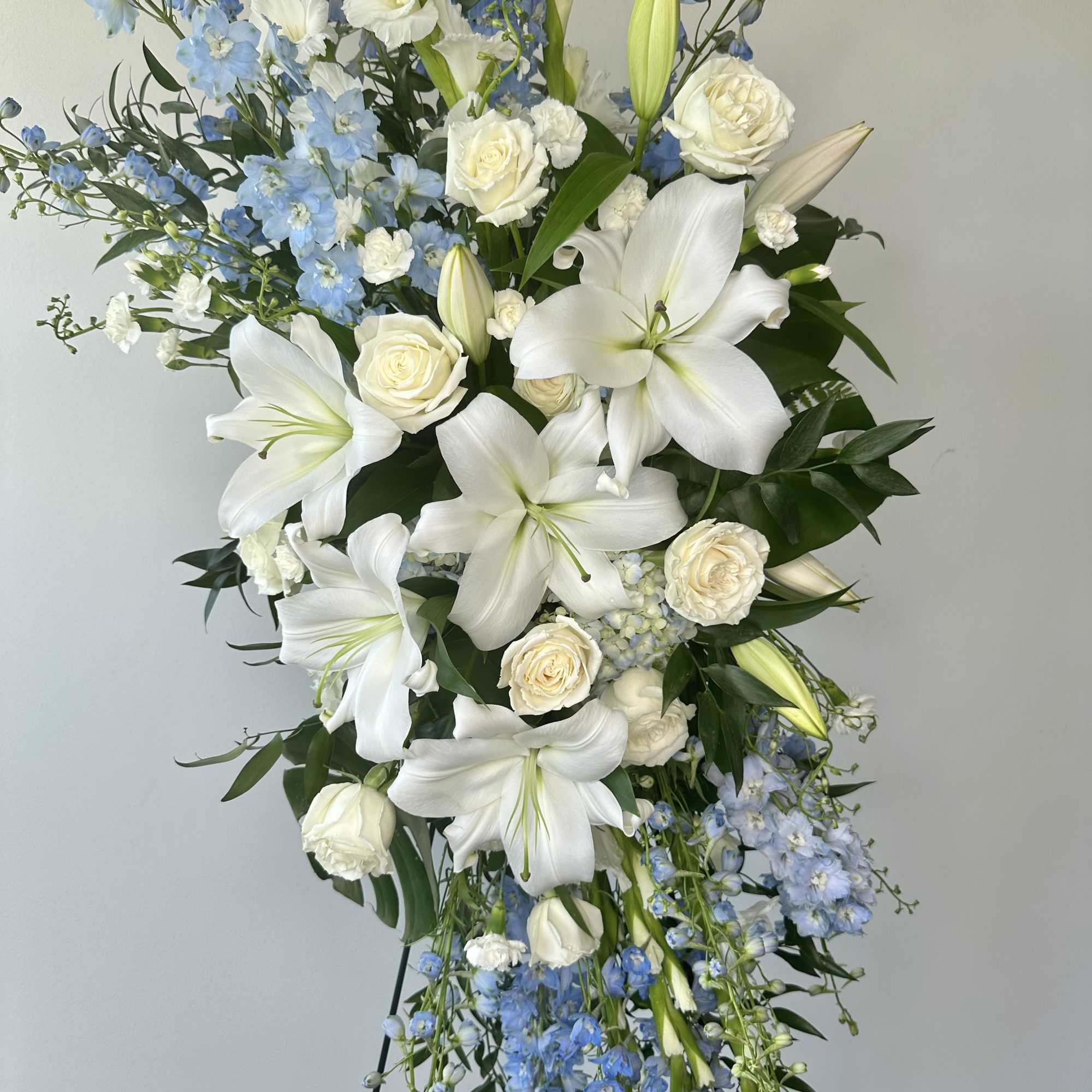 Tall white and blue floral standing spray with lilies and roses