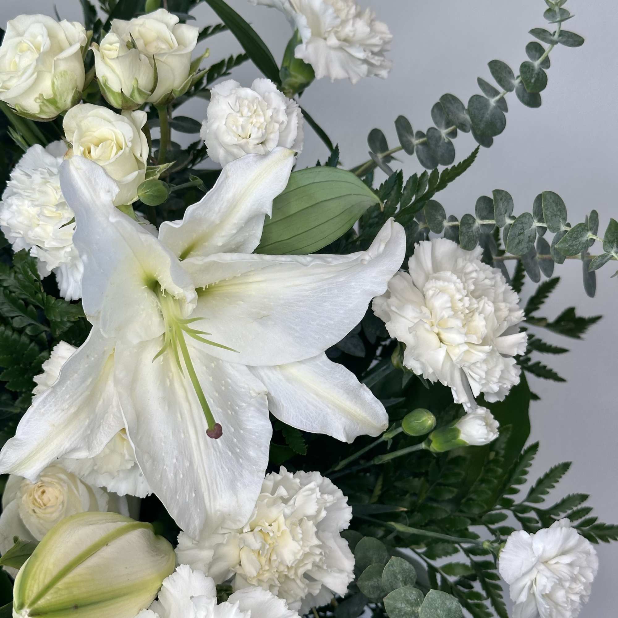 White lilies and carnations with eucalyptus in a bouquet