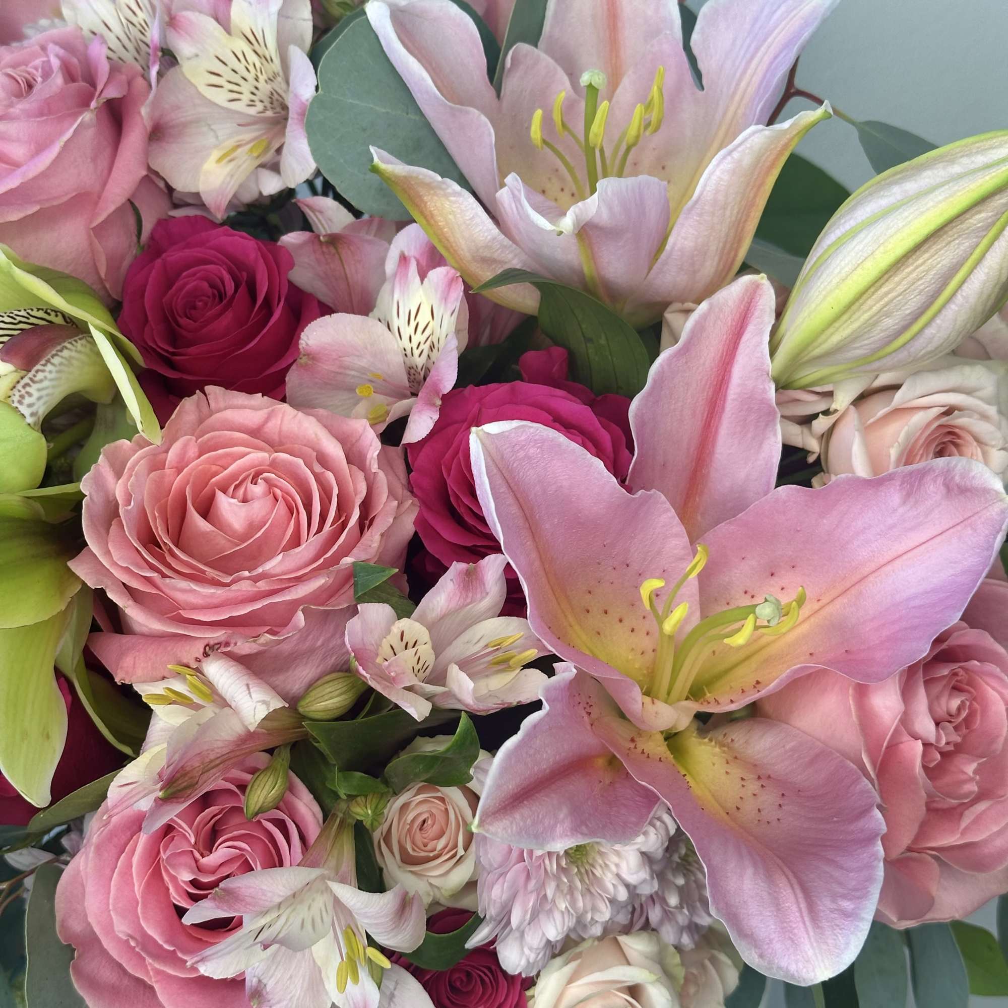Pink lilies and roses in a bouquet with pale filler flowers