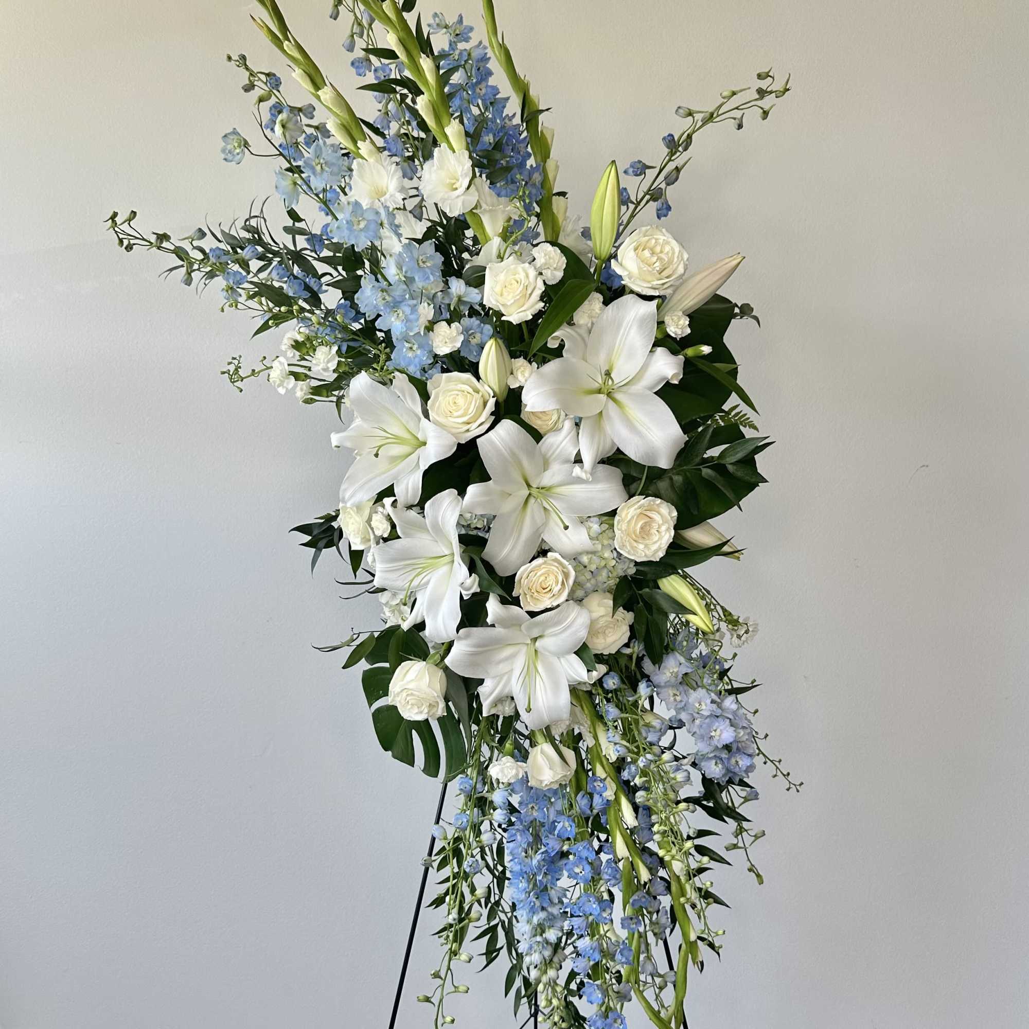 Tall white and blue floral standing arrangement on a black easel