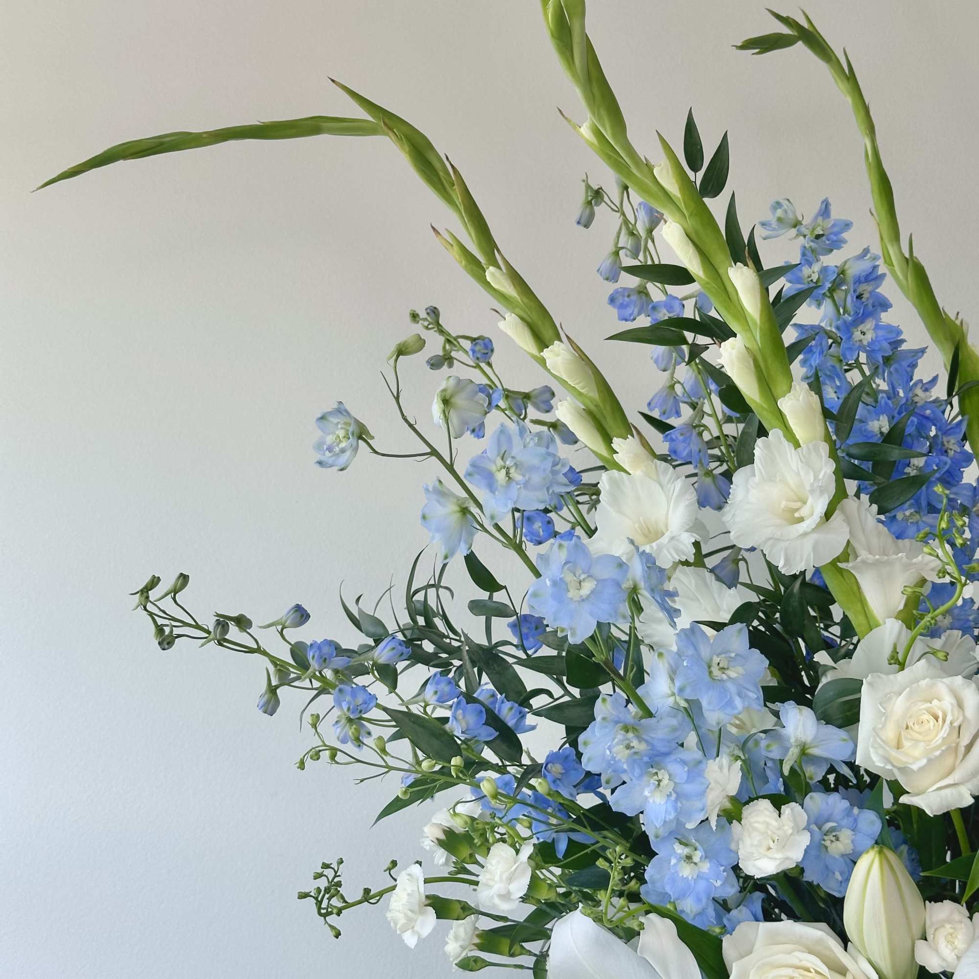 Blue and white floral arrangement with tall green spikes and roses