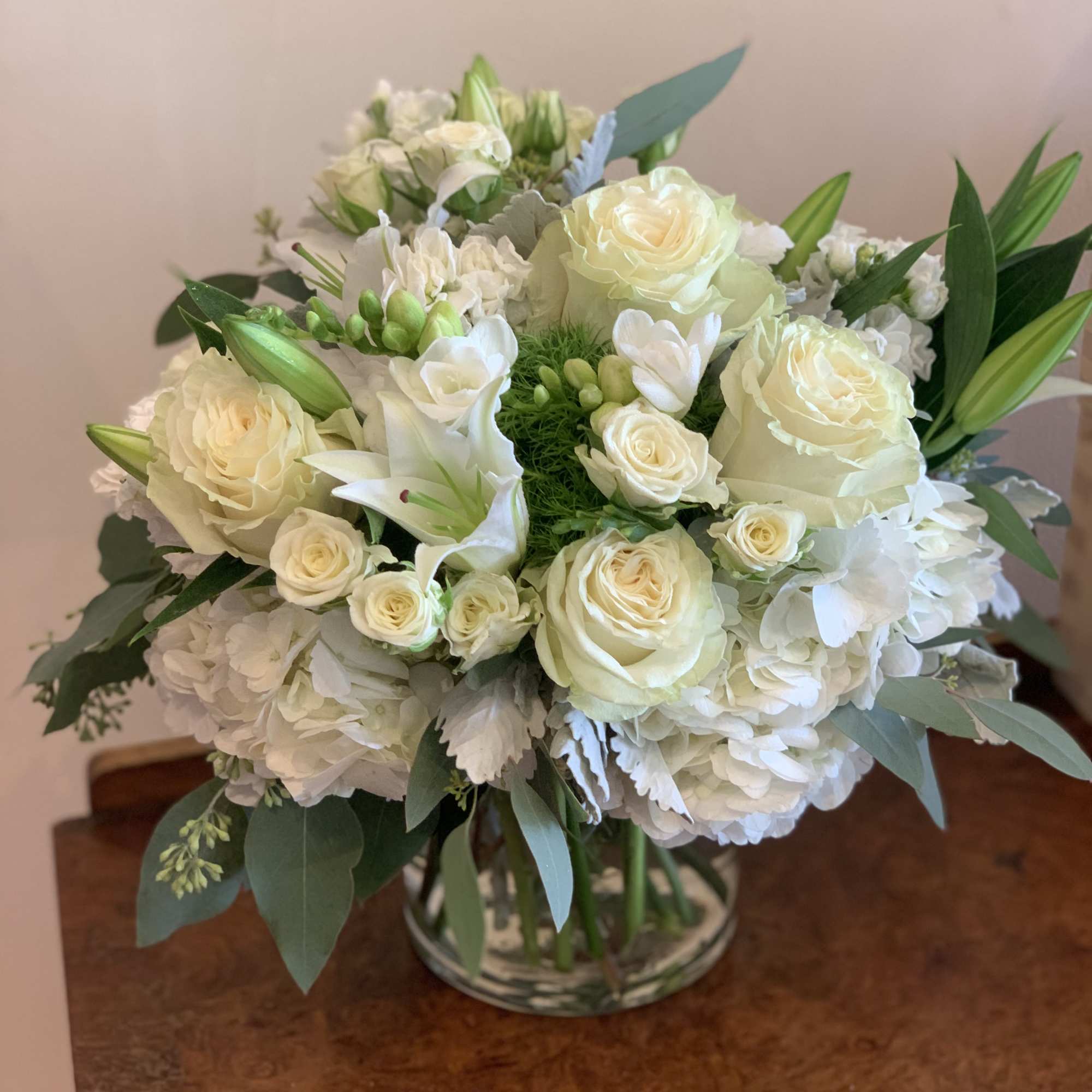 White roses and lilies arranged in a glass vase