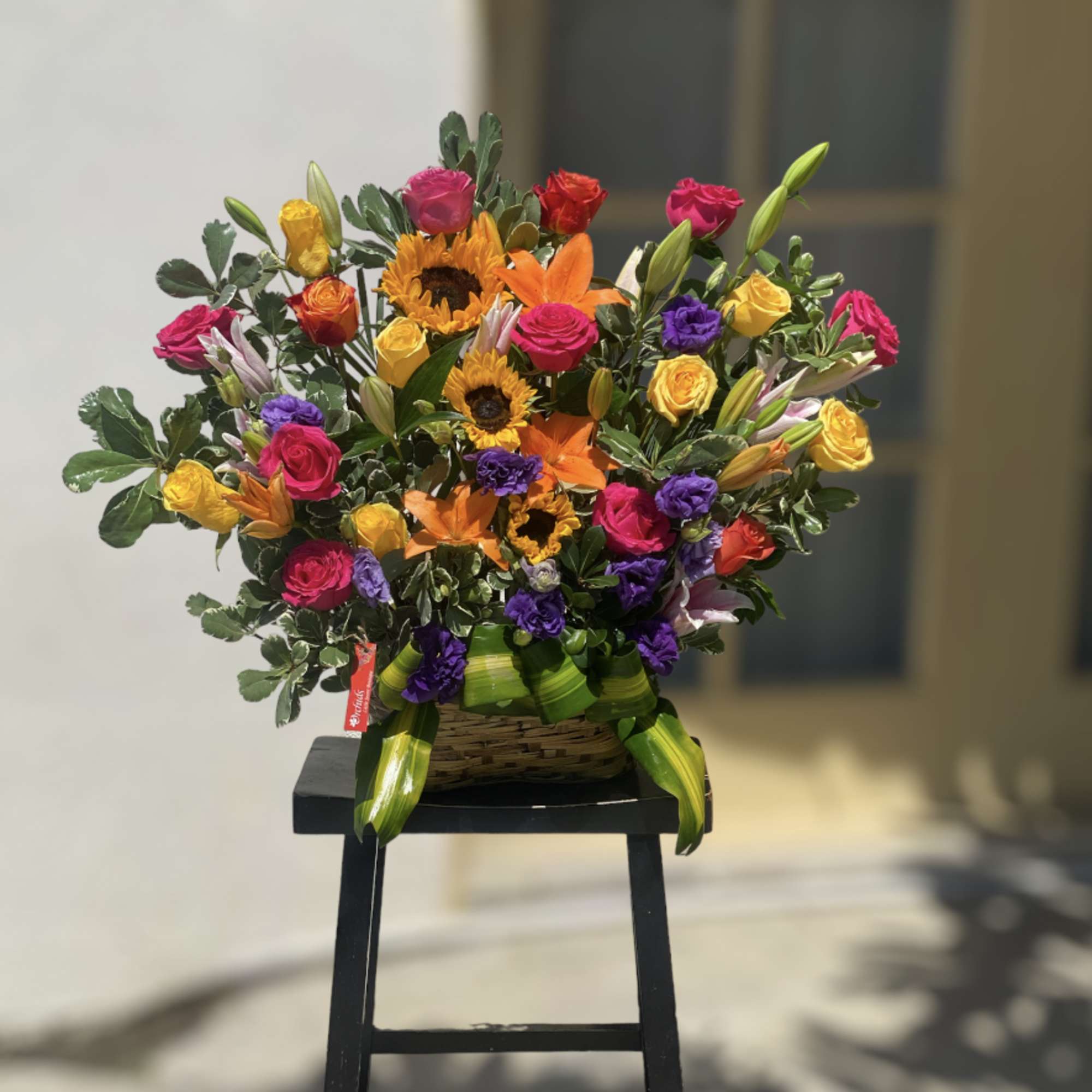 Colorful mixed bouquet with roses, sunflowers, and lilies in a basket