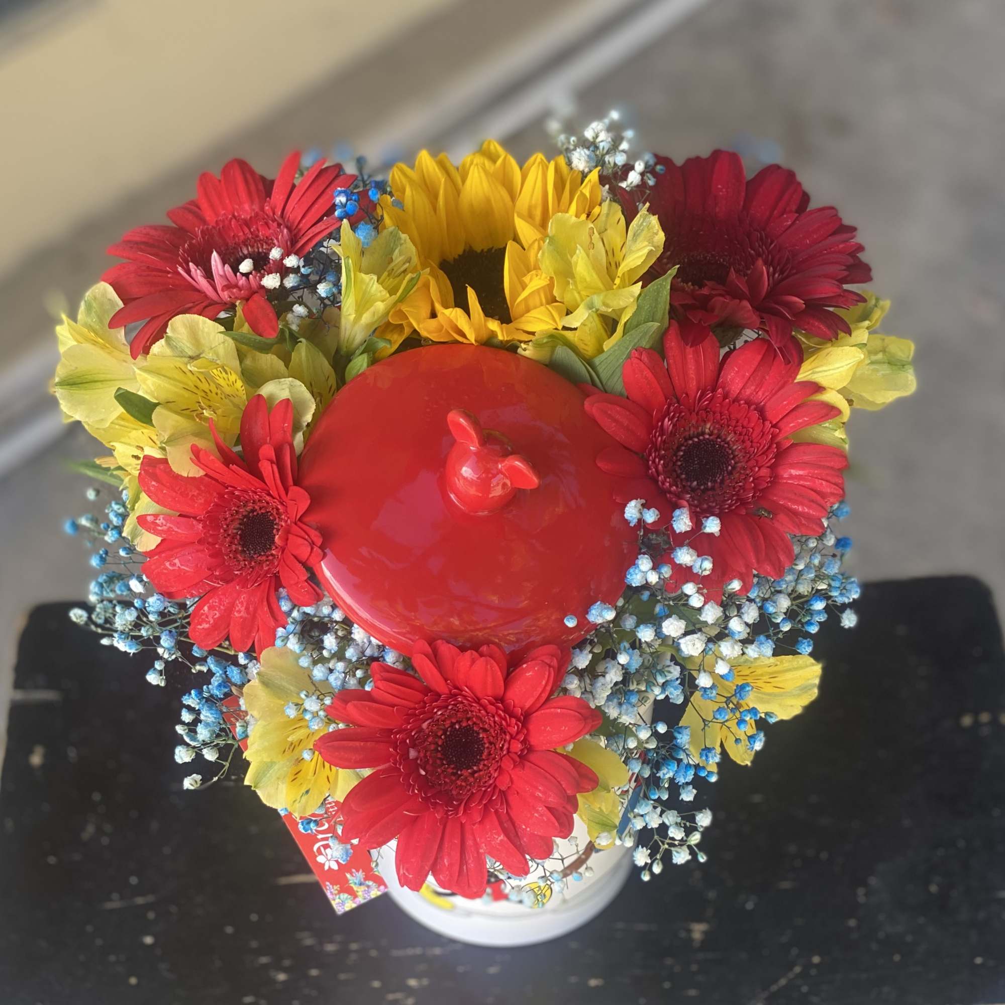 Bright mixed bouquet with red, yellow, and blue flowers in a white container