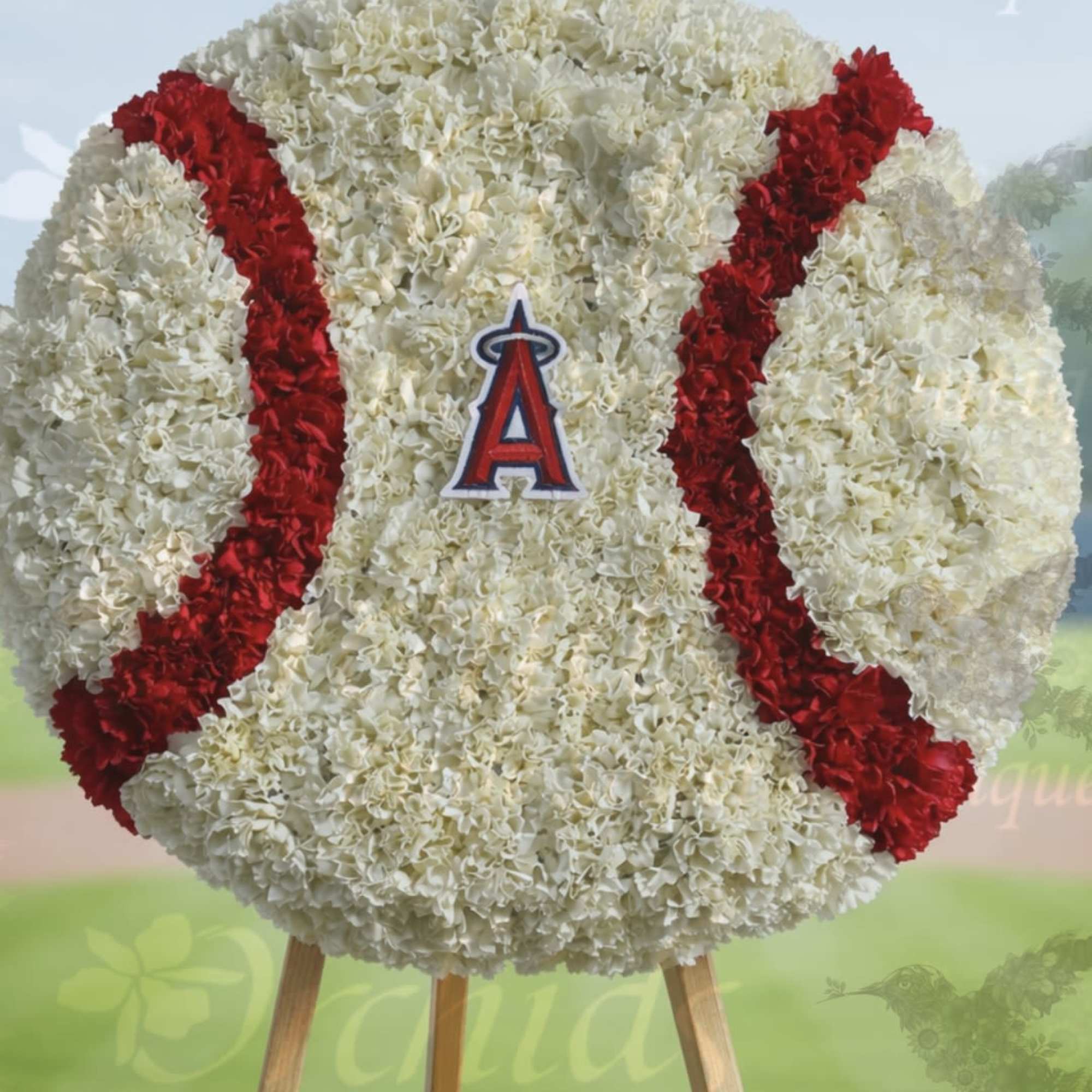 Large round white and red floral arrangement shaped like a baseball on a wooden stand