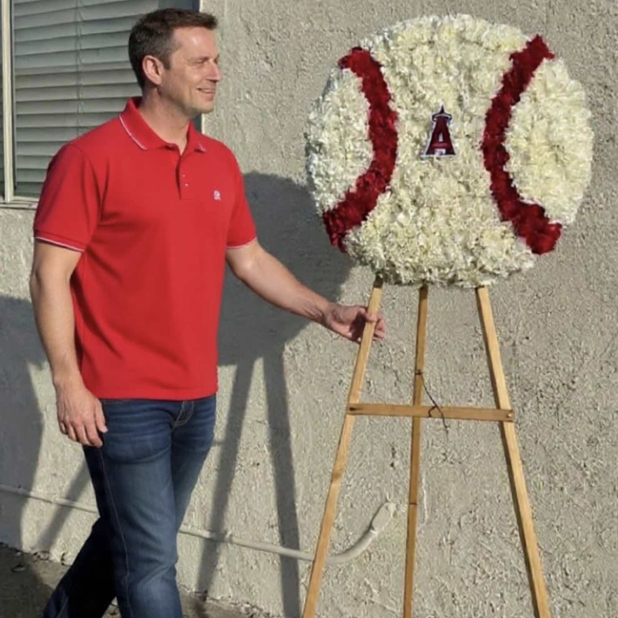 Large round white and red floral baseball design on a wooden easel outdoors