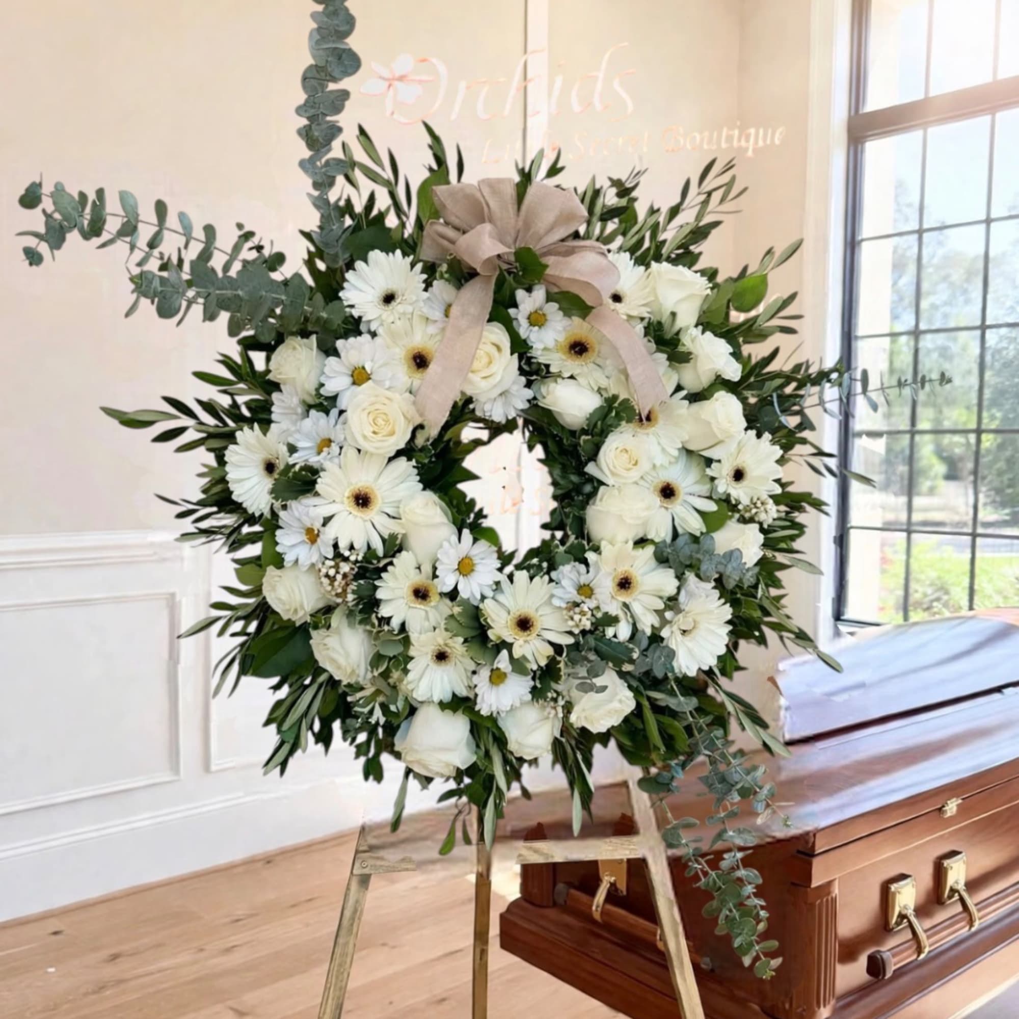White floral wreath on an easel beside a casket
