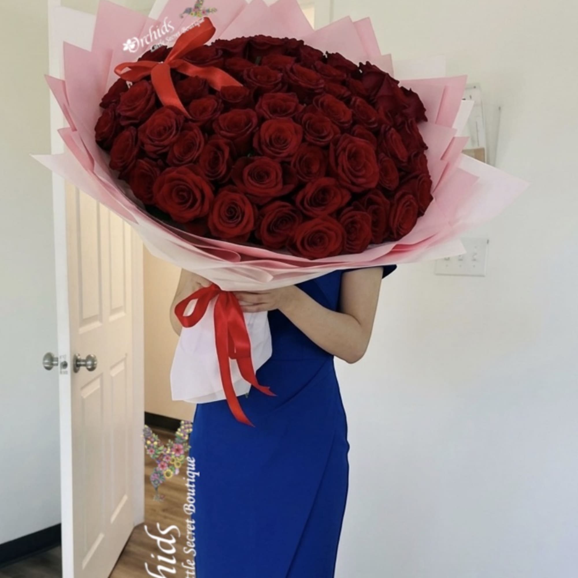 Large bouquet of red roses wrapped in pink paper with a red ribbon