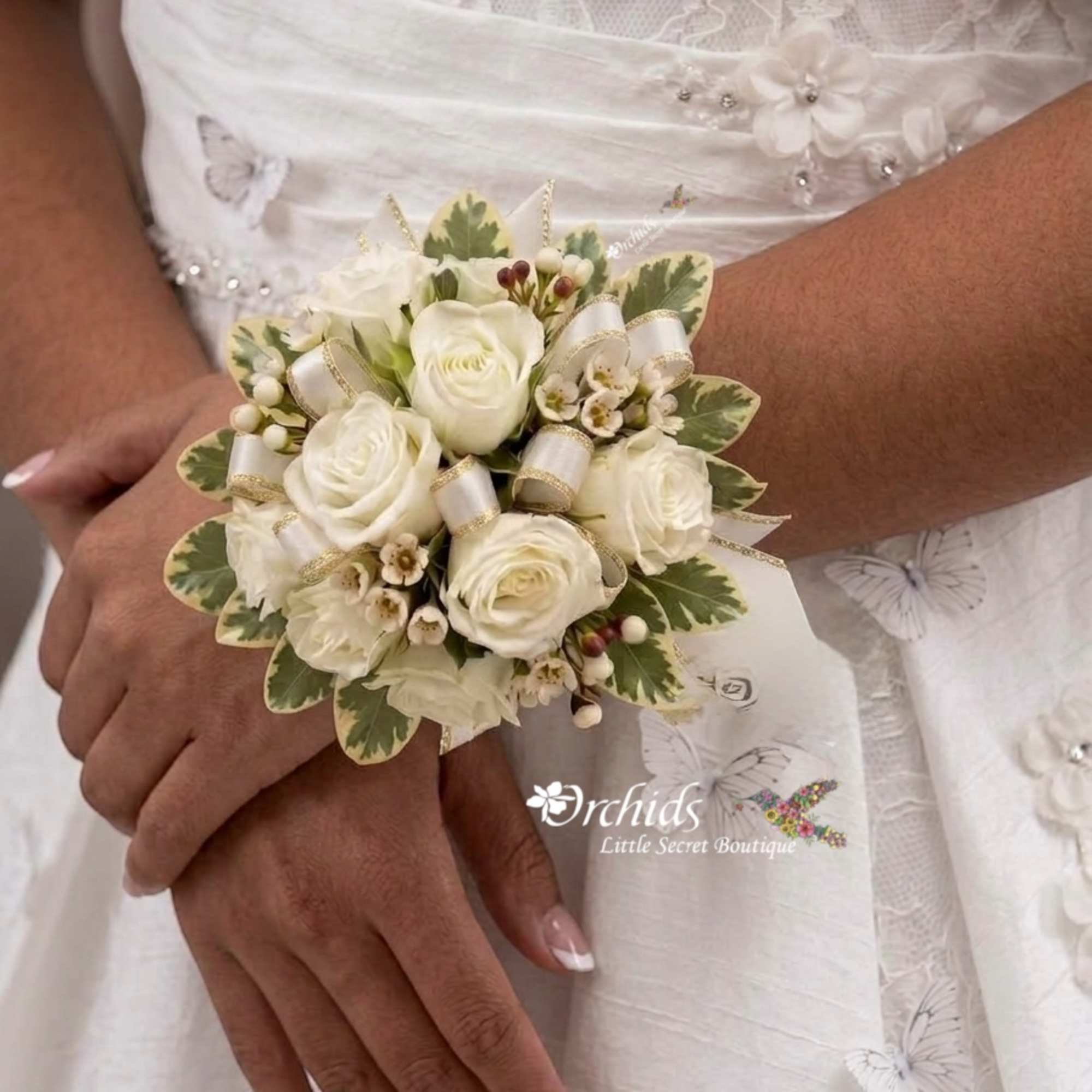 White rose wrist corsage with ribbon and berries on a bride's wrist