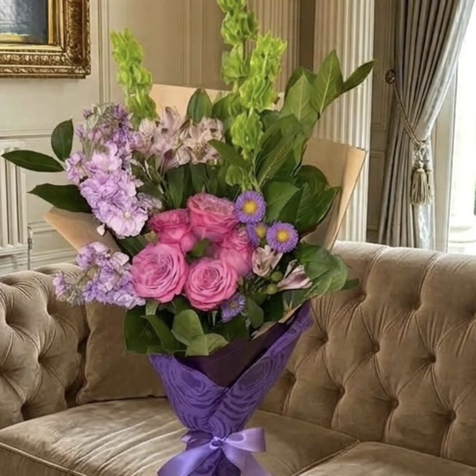 Bouquet of pink roses and purple flowers wrapped in purple paper