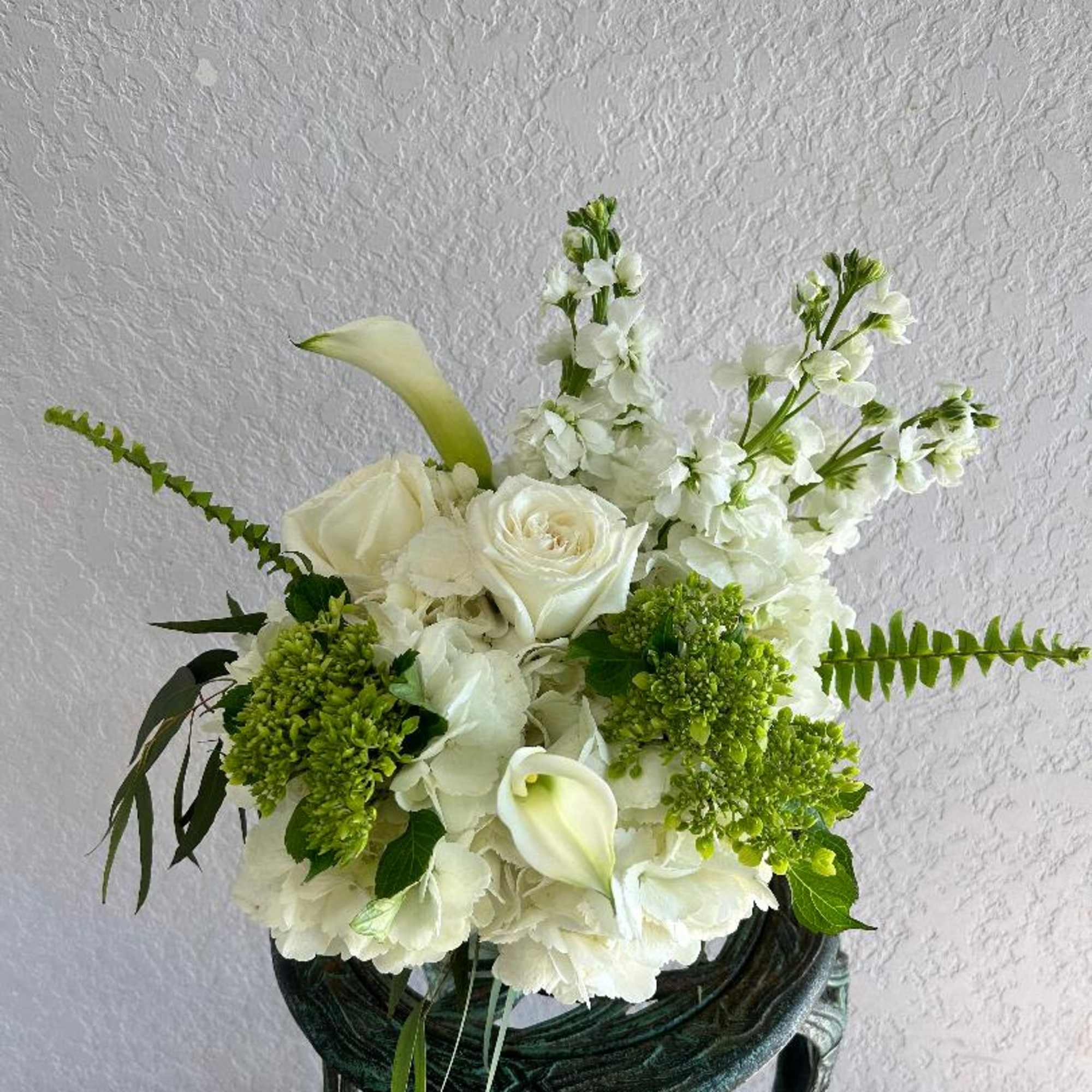 A short compact arrangment of high end white and green flowers such