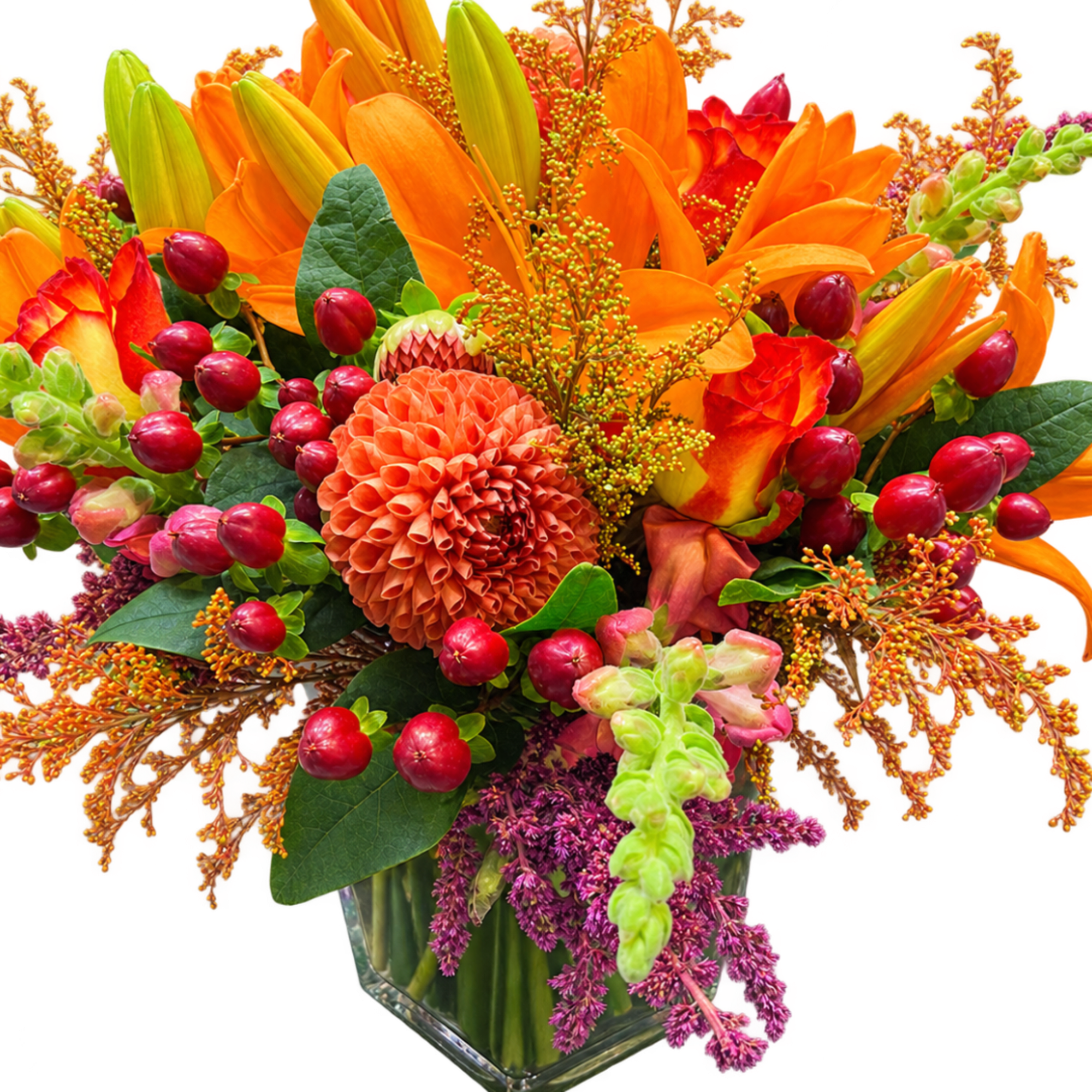 Orange lilies and red blooms in a clear glass vase