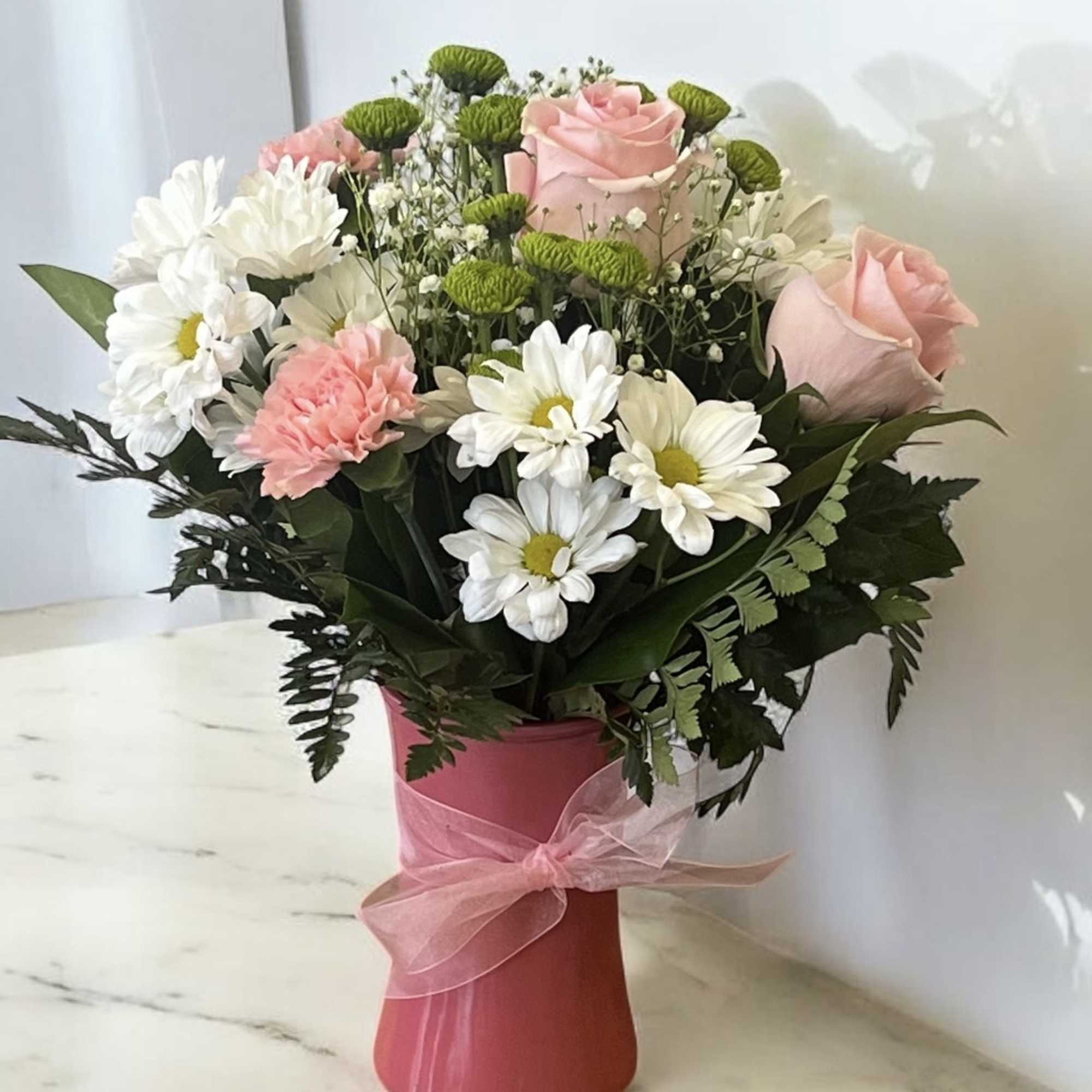 Pink roses and white daisies in a pink vase with a ribbon