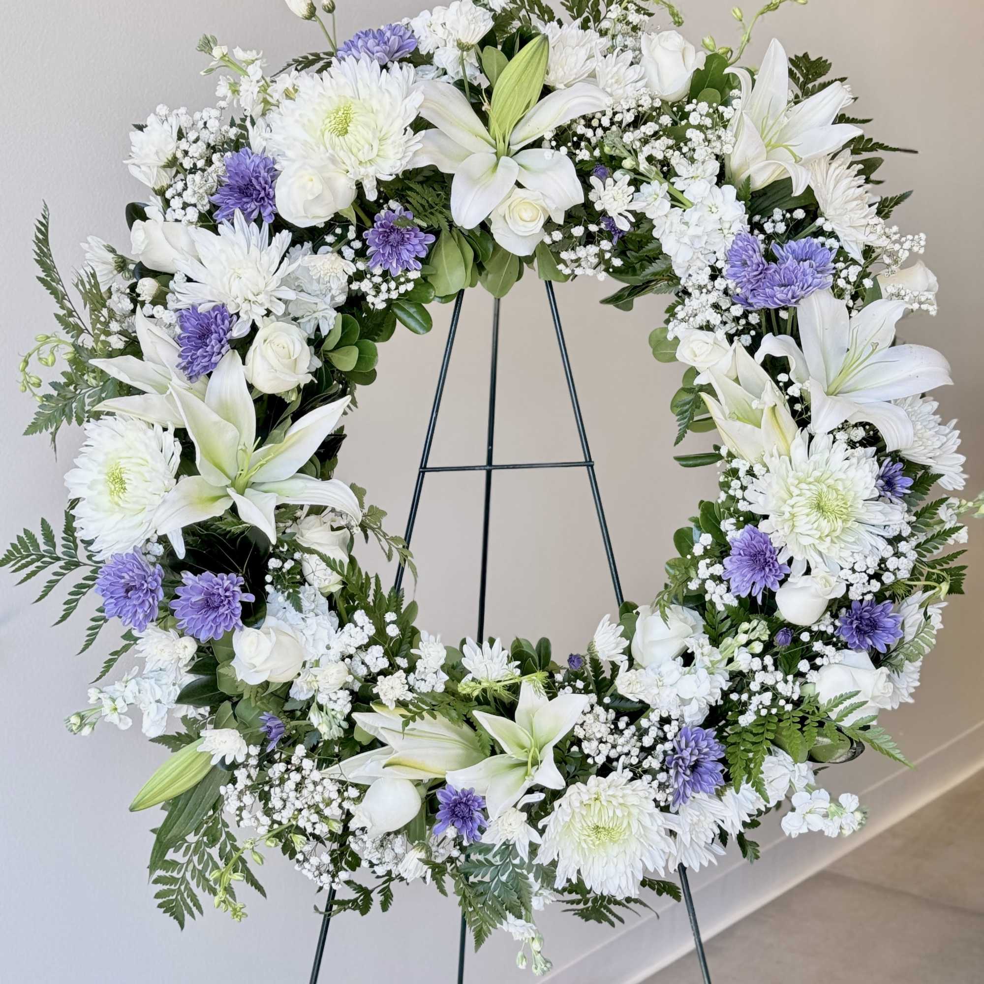 White and lavender floral wreath on a metal stand