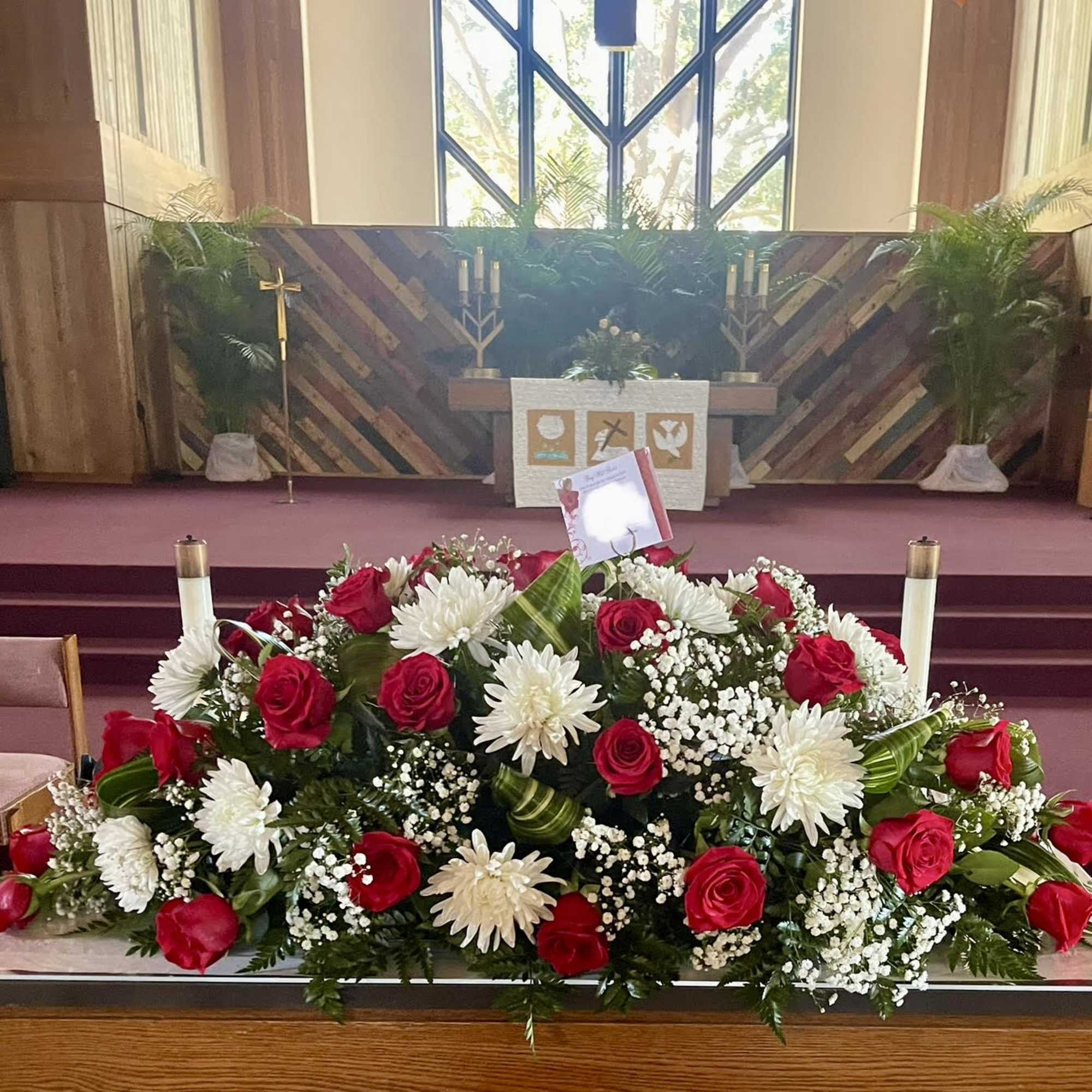 Casket spray with red roses and white daisies in a church