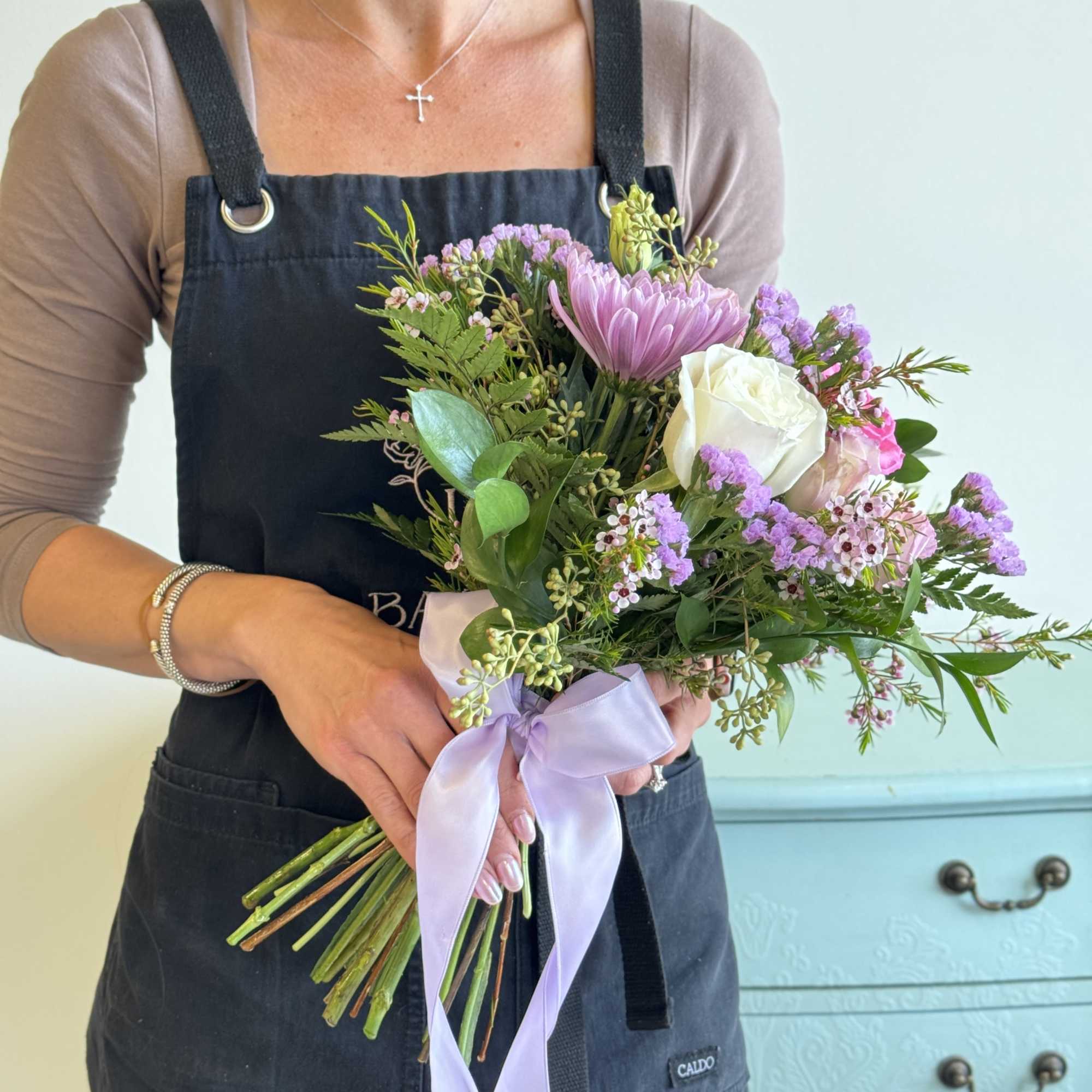 Woman holding a pastel bouquet with a lavender ribbon