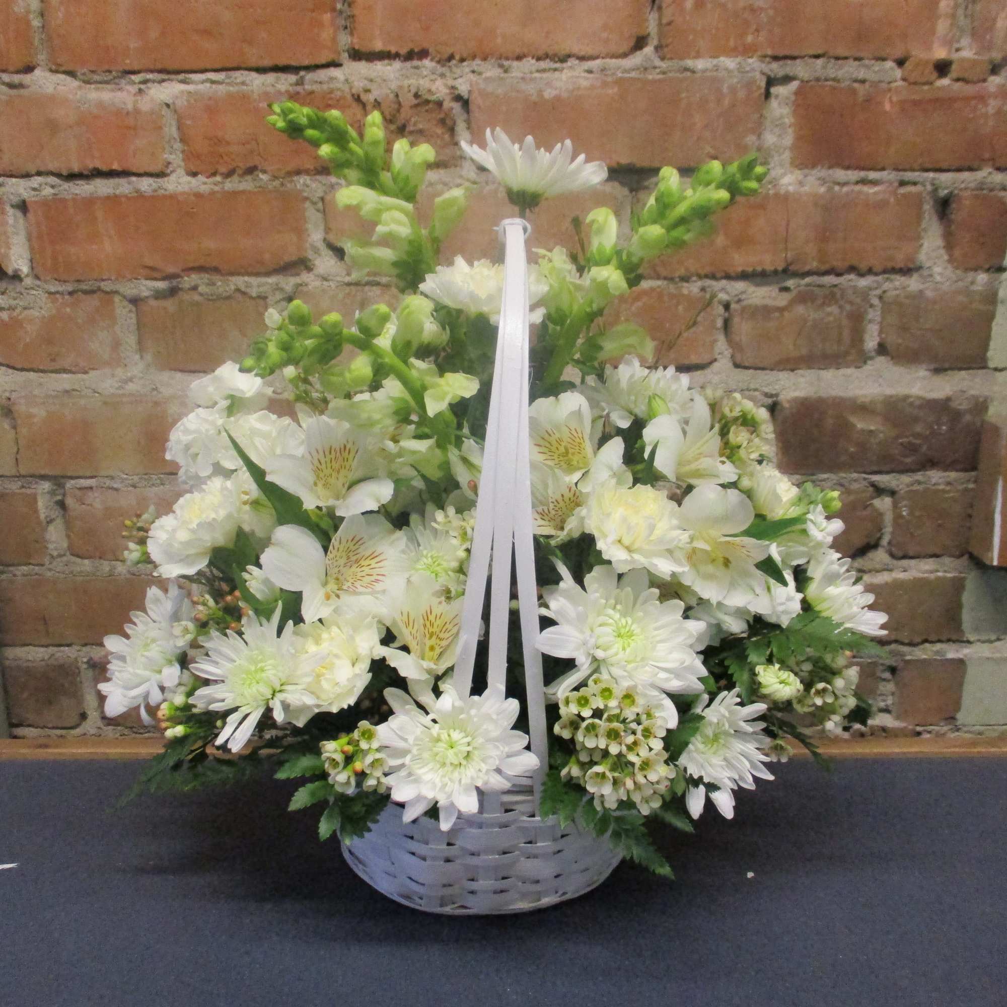 White floral basket arrangement with daisies and lilies in a white basket