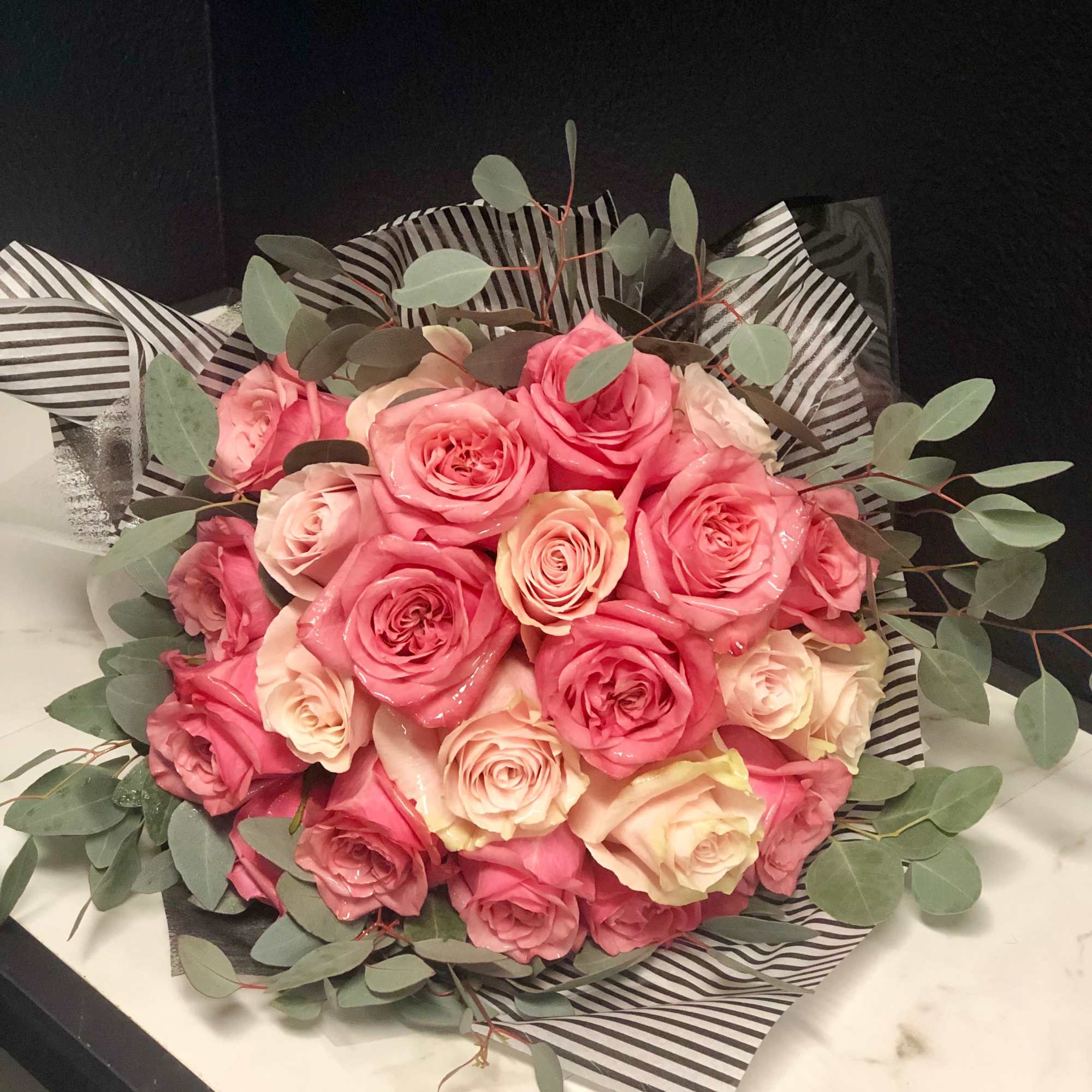 Bouquet of pink and cream roses wrapped in striped paper