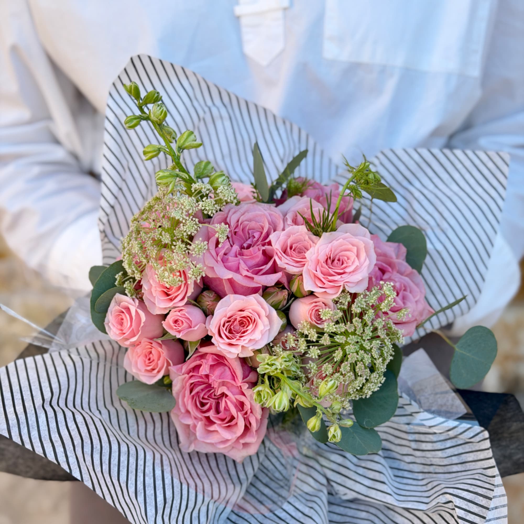 Pink rose bouquet wrapped in striped paper, photo 2 of 3