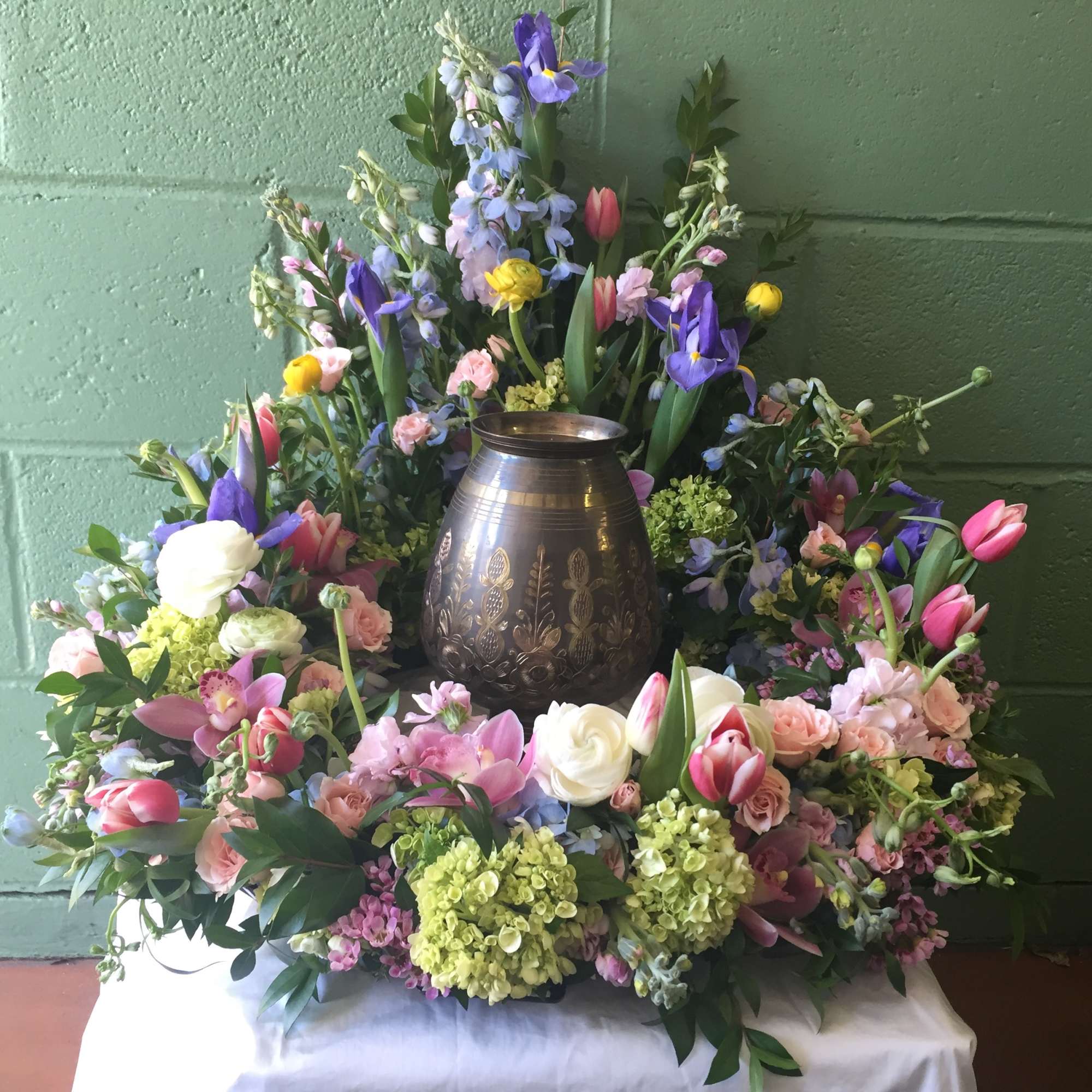 Floral wreath around a metal urn with pink, purple, white, and yellow blooms