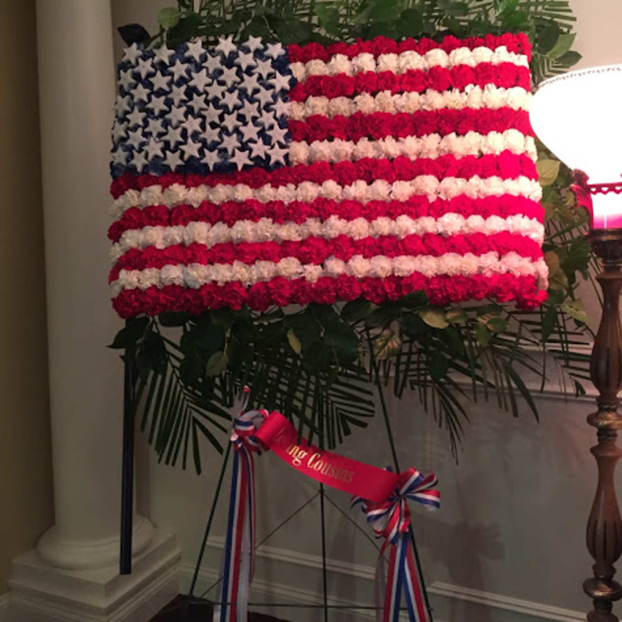 Floral American flag display on an easel with red, white, and blue flowers