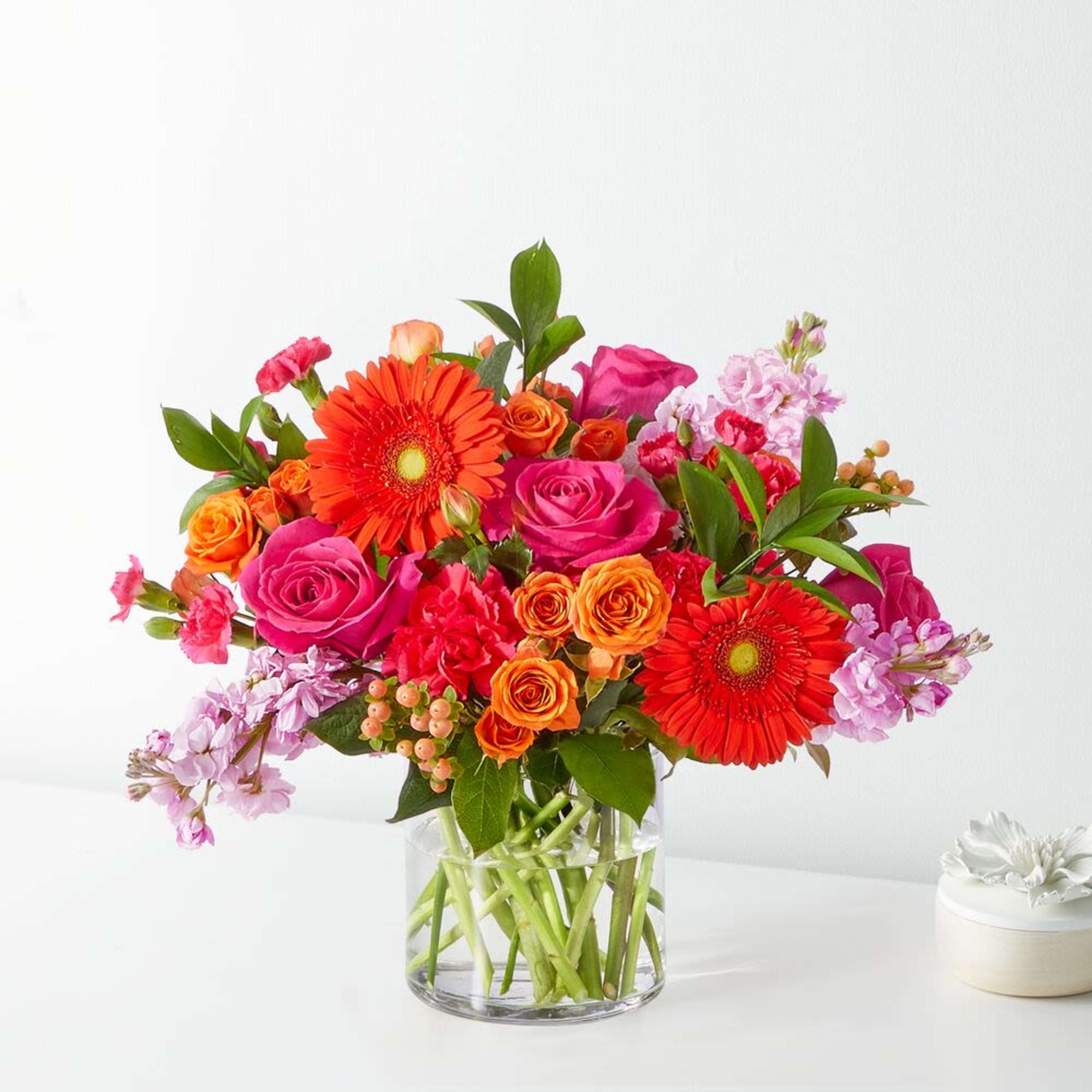 Bright mixed bouquet in a clear glass vase with pink and orange blooms