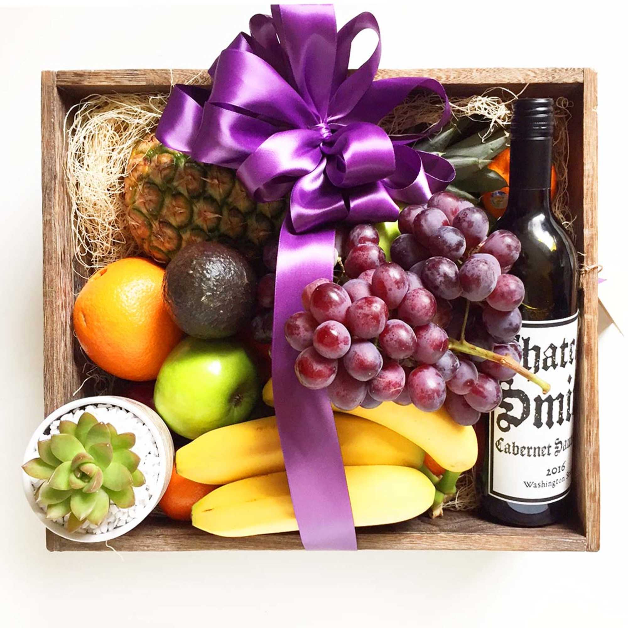 Gift basket with fruit, a wine bottle, and a succulent in a wooden box