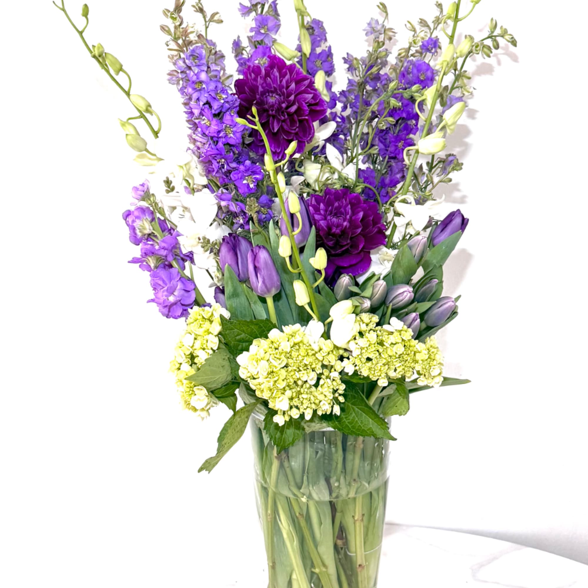 Purple and white mixed bouquet in a clear glass vase