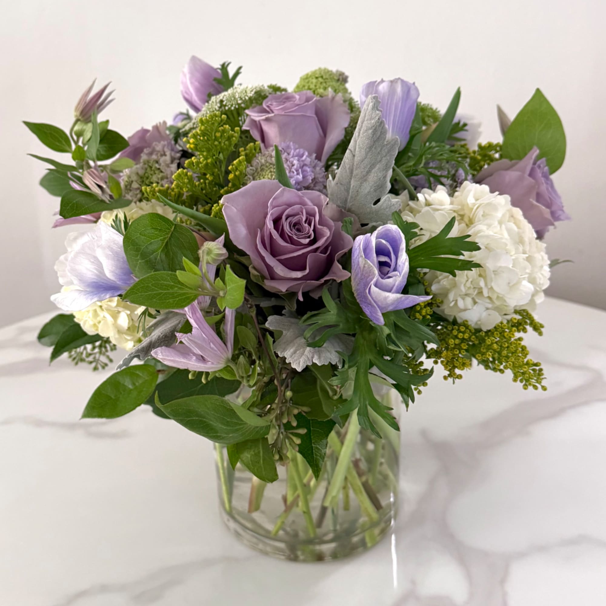 Lavender roses and white hydrangeas in a clear glass vase