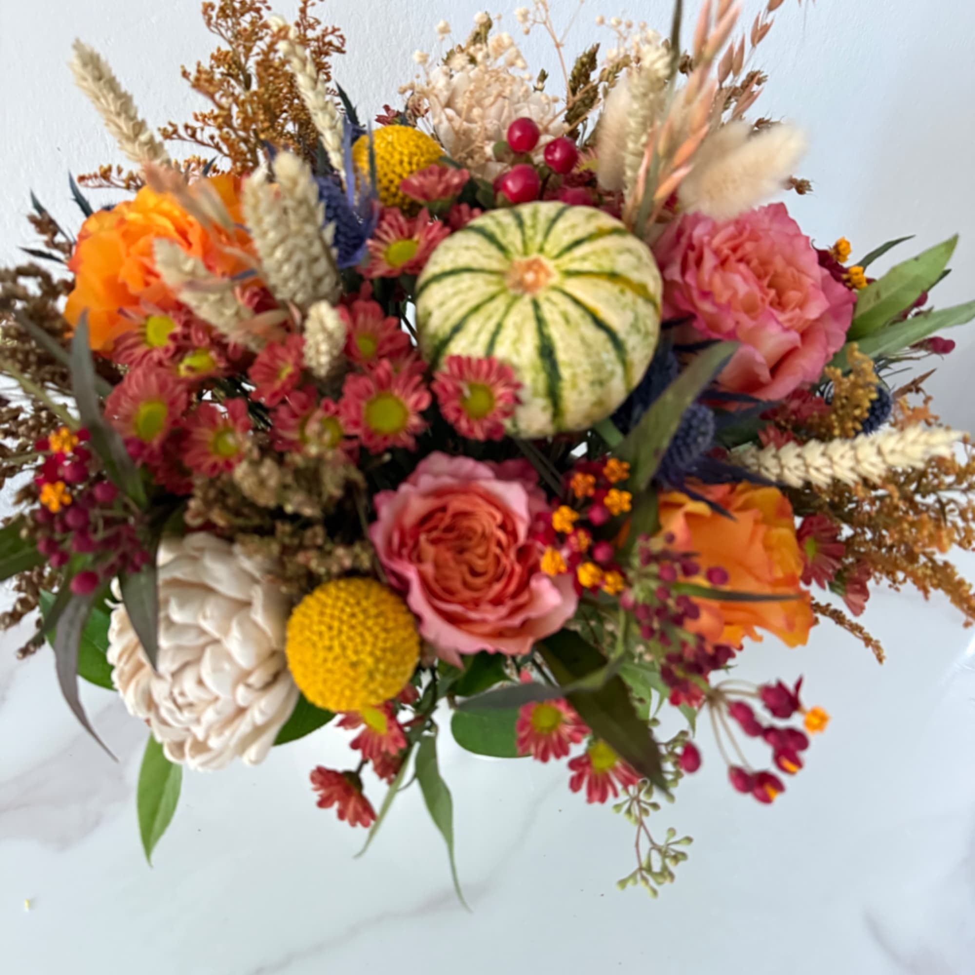 Mixed bouquet with roses, mums, and a small decorative pumpkin