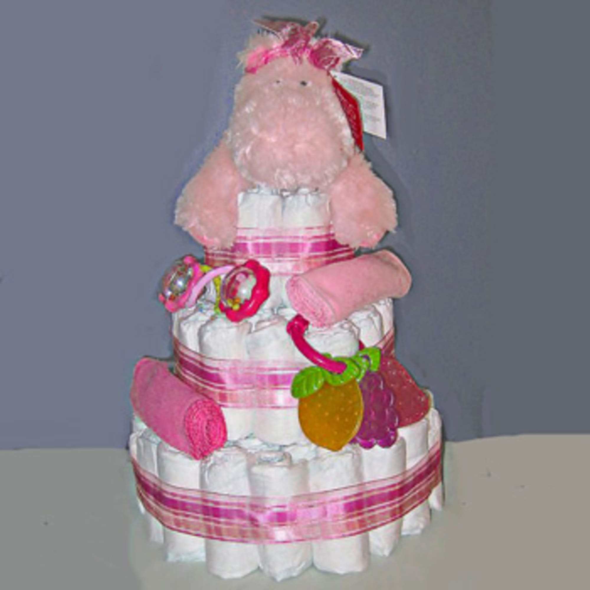 Pink teddy bear atop a tiered diaper cake with ribbons and baby toys