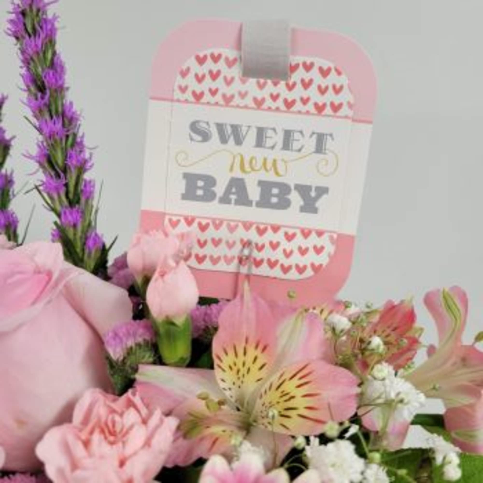 Pink baby gift arrangement with flowers and a "Sweet New Baby" sign