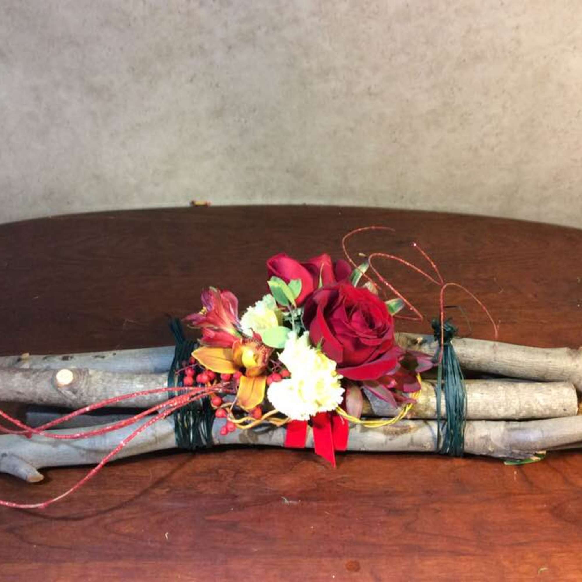 Small floral arrangement with red roses and white blooms on bundled branches