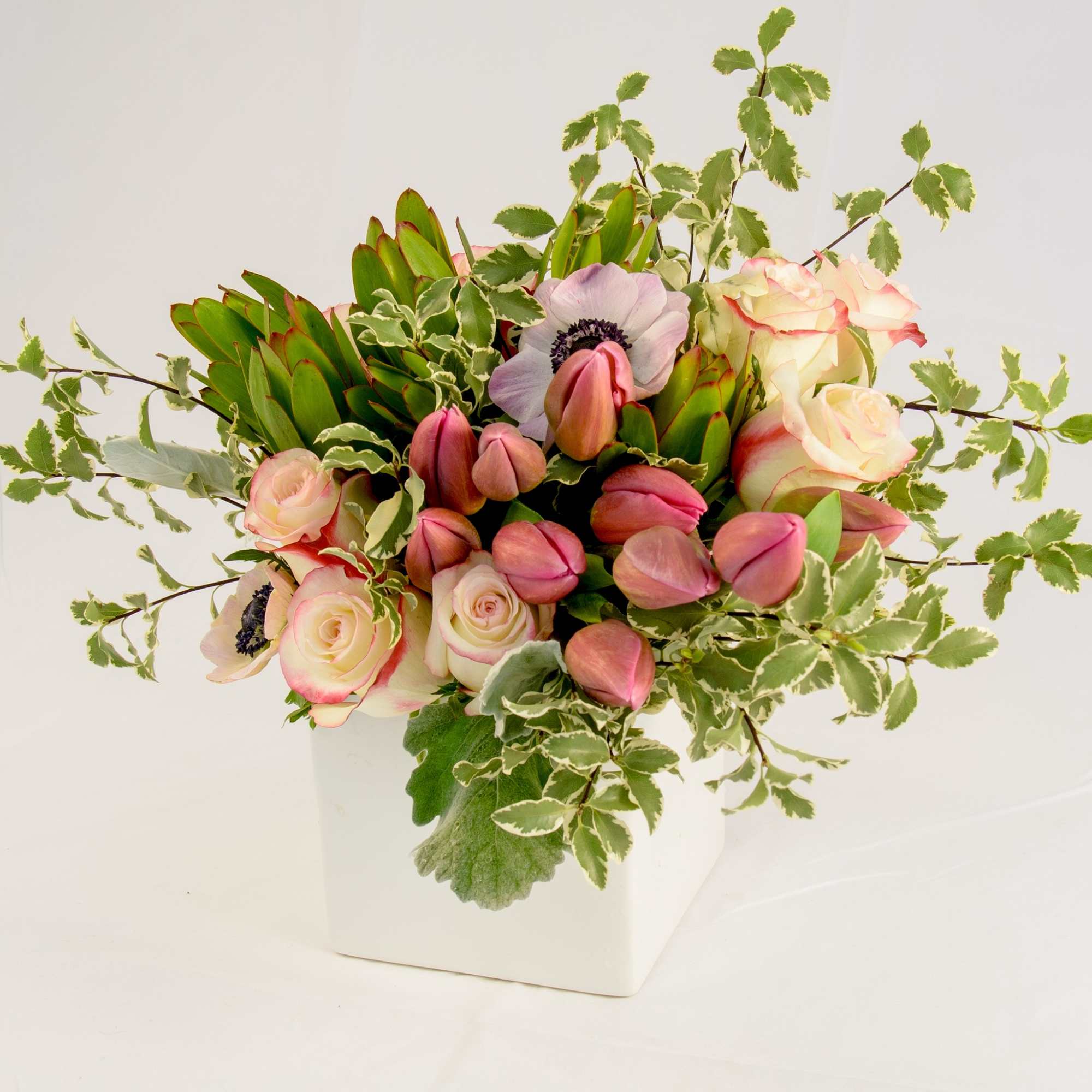 Pink tulips and pale roses in a white square vase