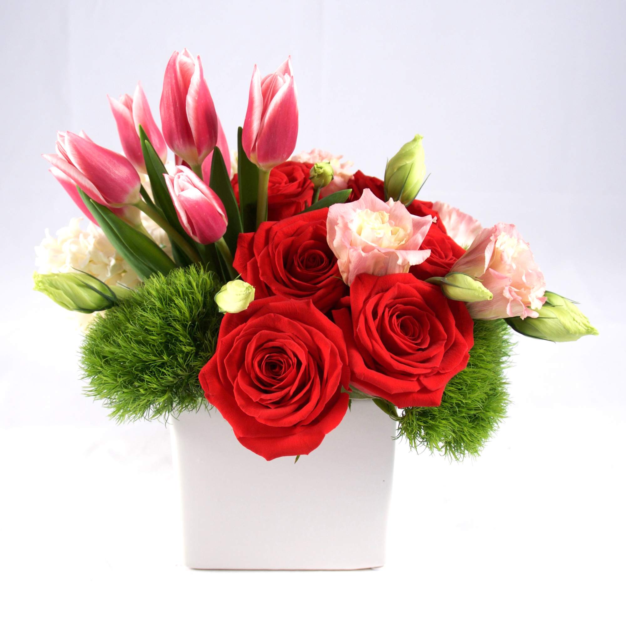 Pink tulips and red roses in a white square vase