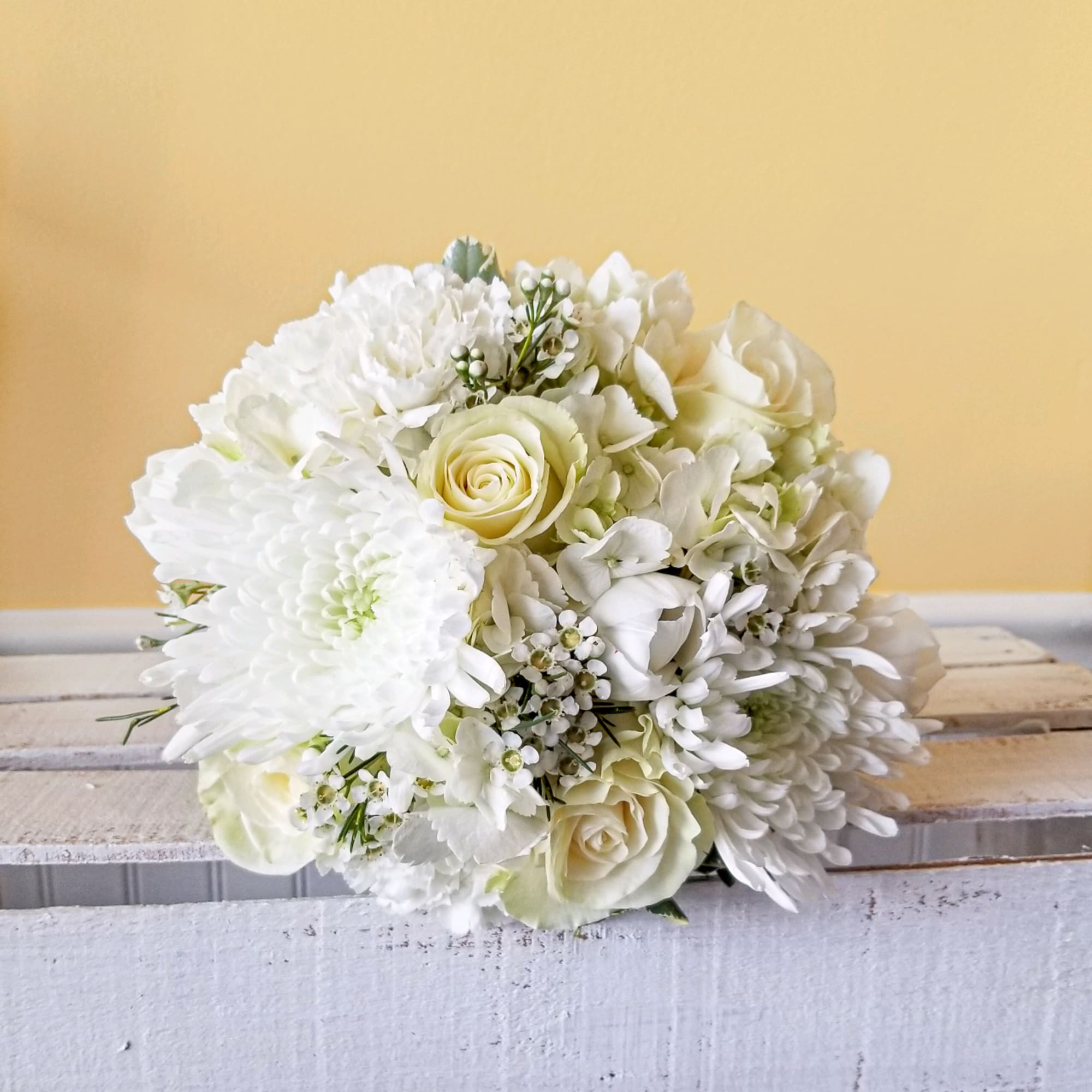 All white mixed flower handheld bouquet.  Flowers arrangements in a tighter