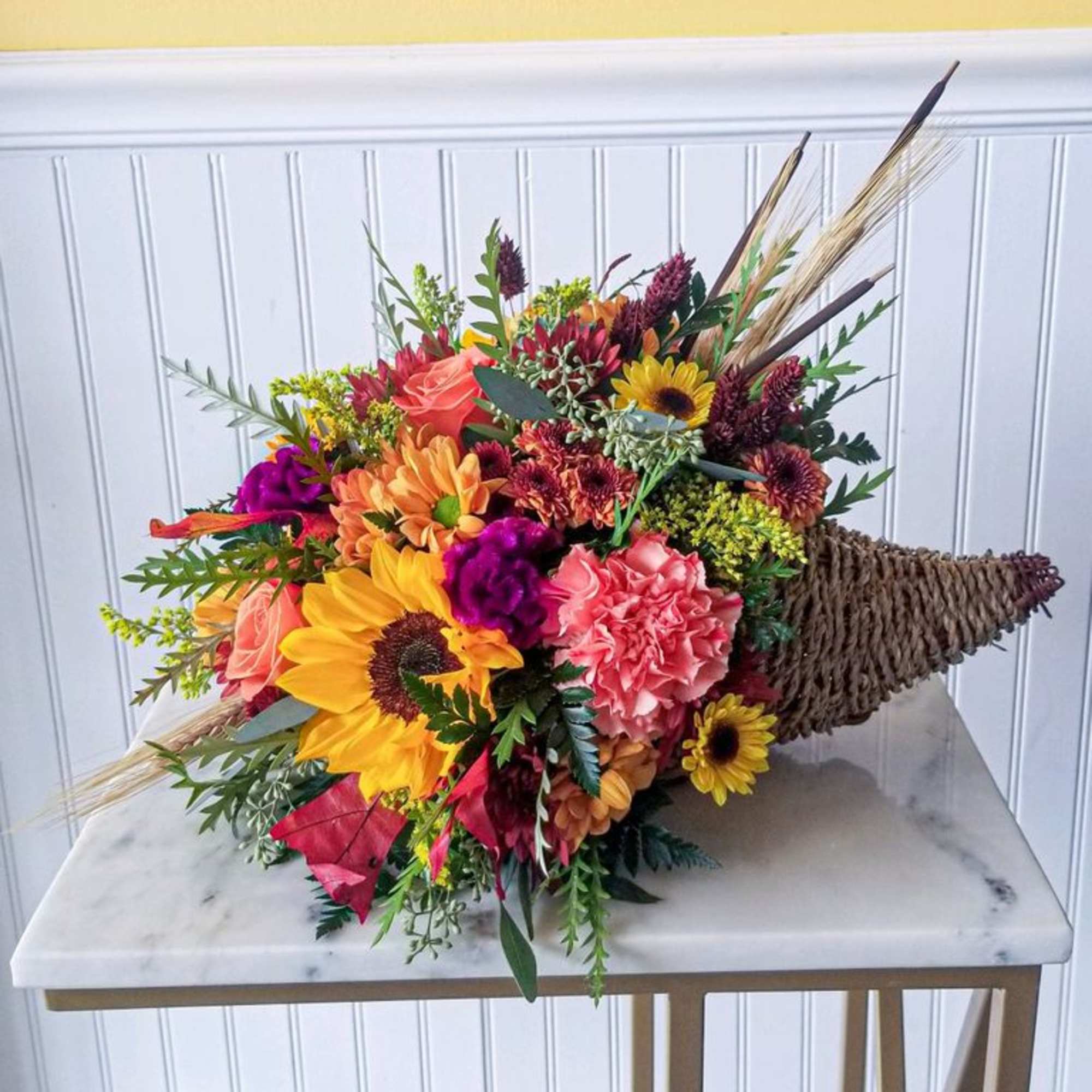 Bright mixed bouquet with sunflowers, roses, and carnations in a woven cone holder