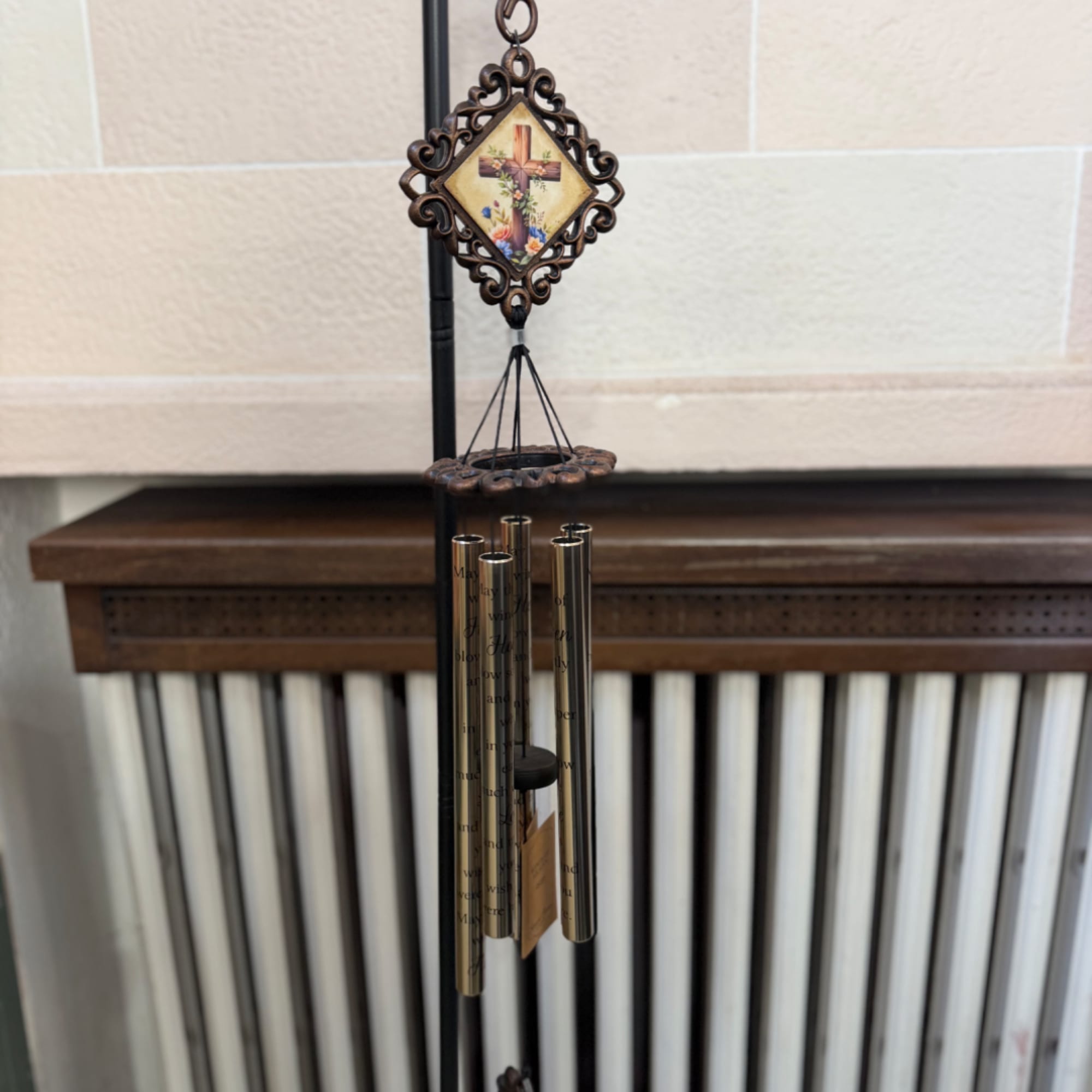 Decorative wind chime with a cross medallion hanging indoors