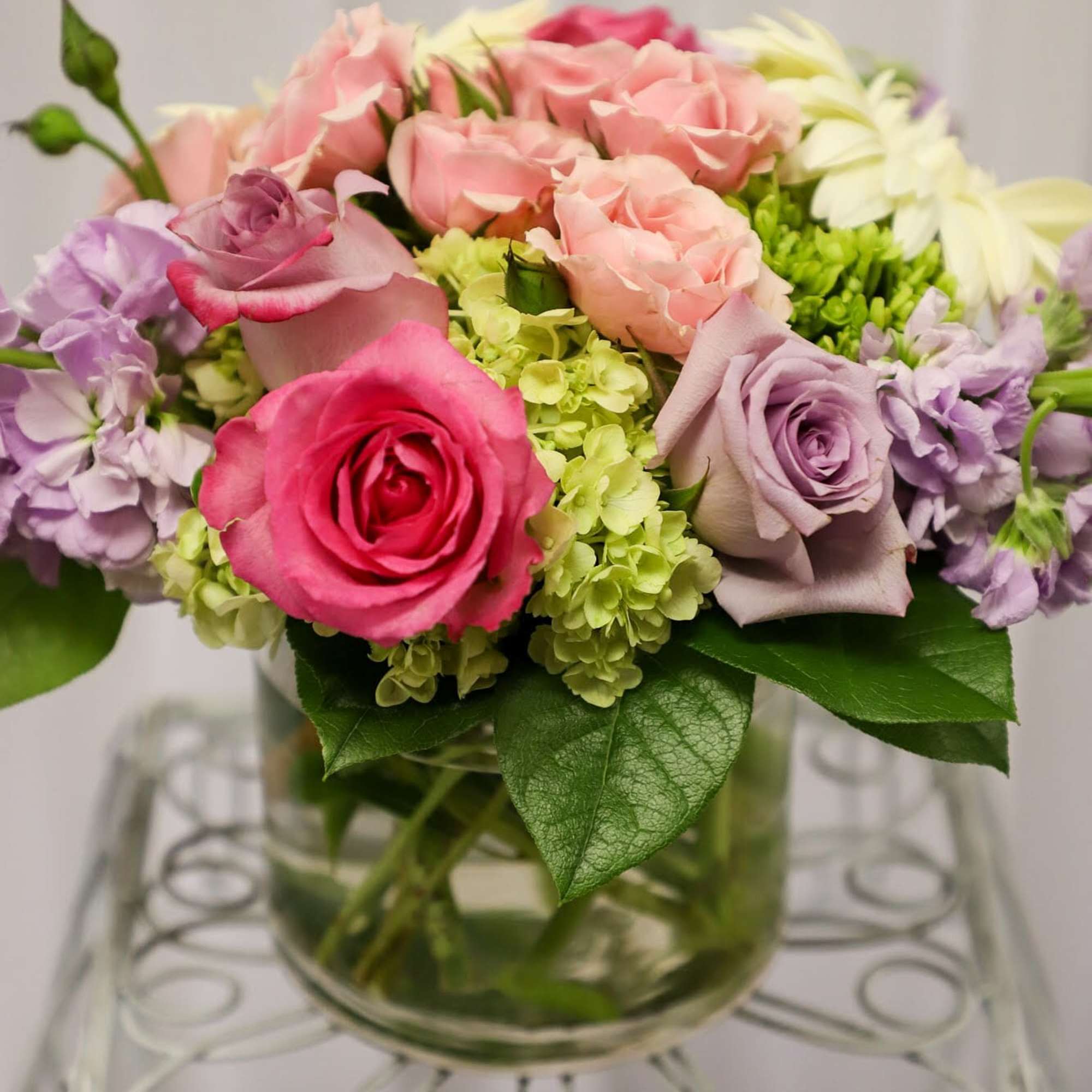 Mixed pink, lavender, and white roses arranged in a glass vase