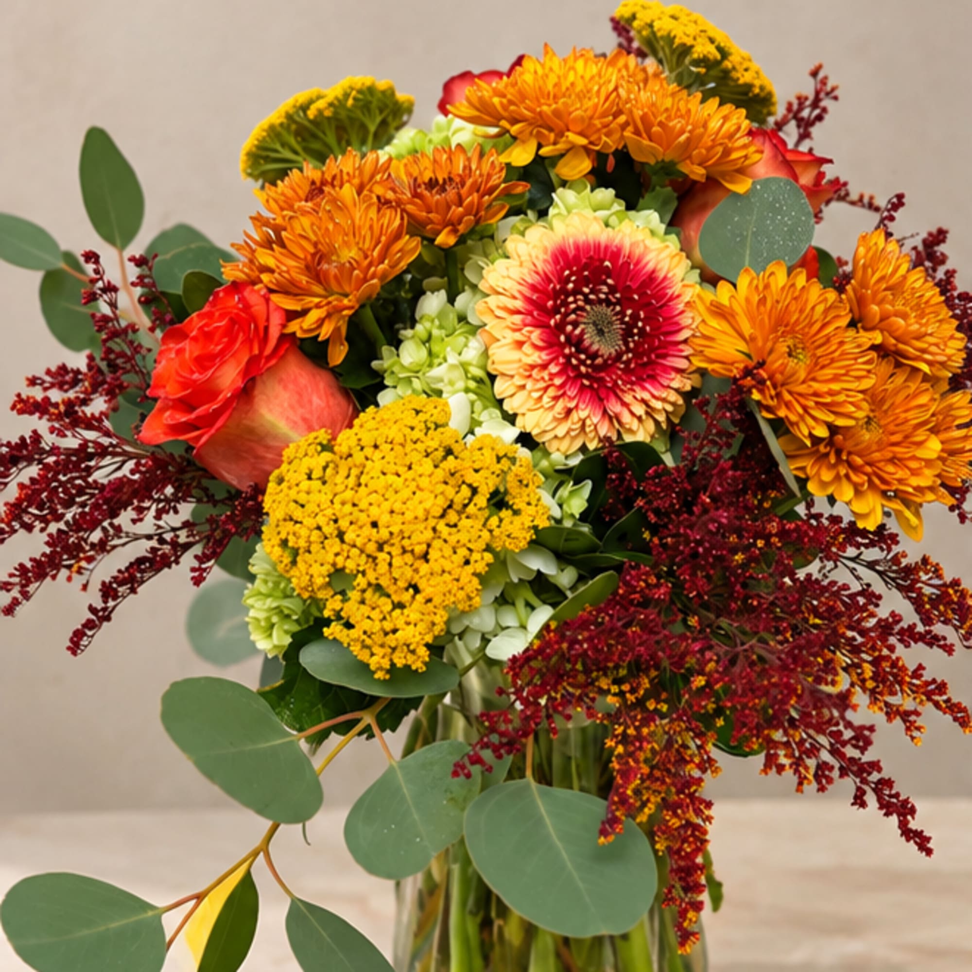 Mixed bouquet of orange, yellow, and red flowers in a glass vase