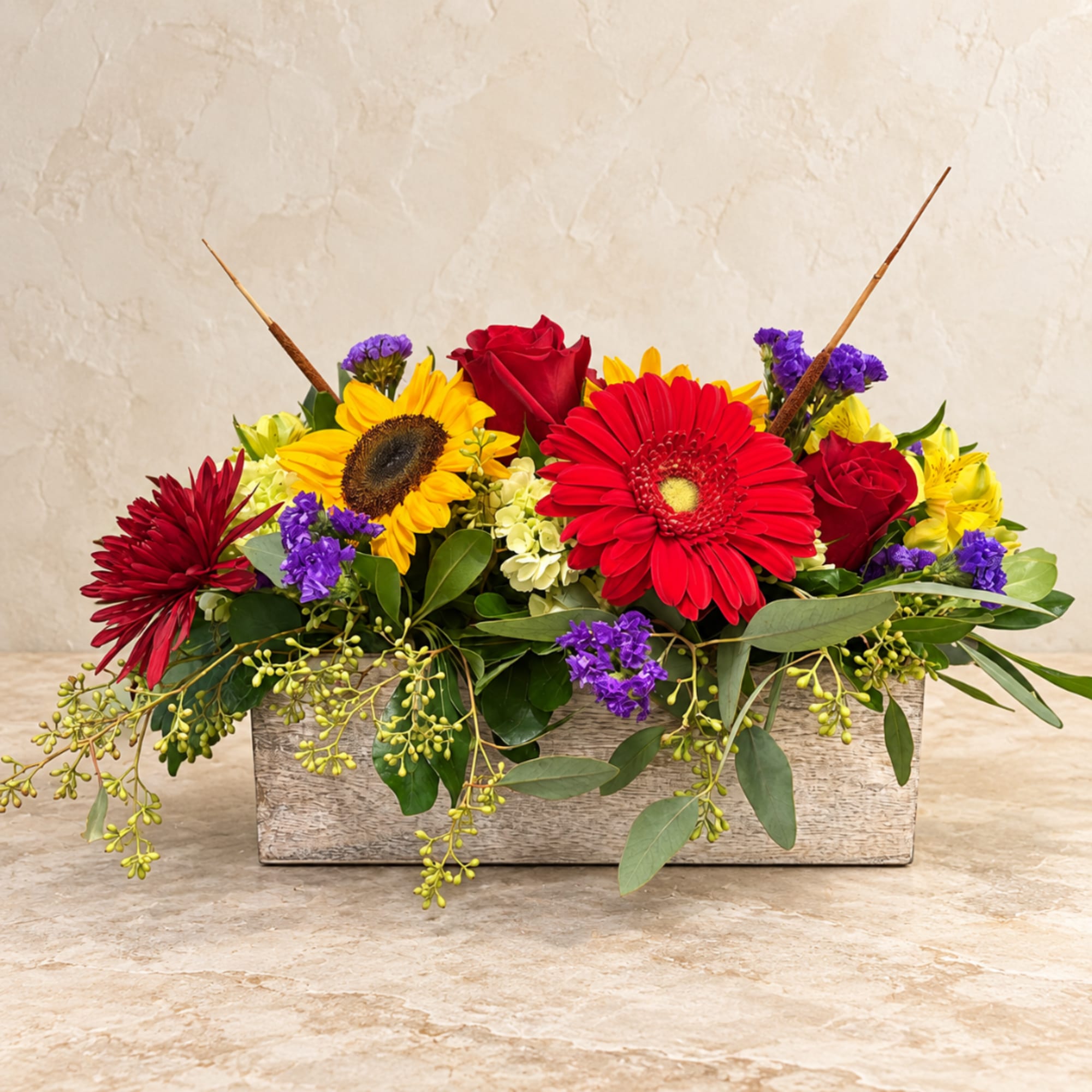 Mixed bouquet in a rectangular wooden box with red, yellow, and purple flowers