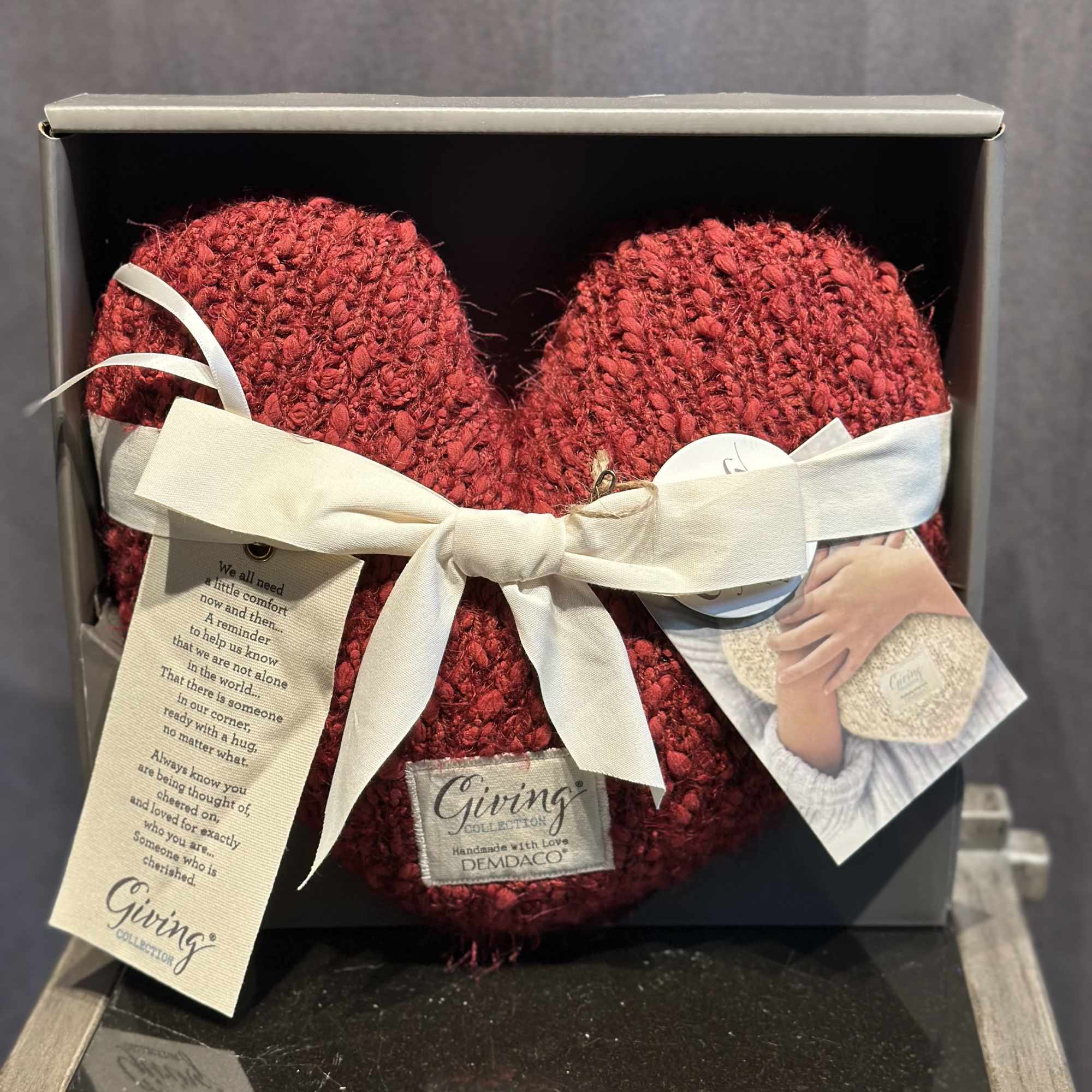 Two red knitted heart ornaments in a gift box with a white ribbon