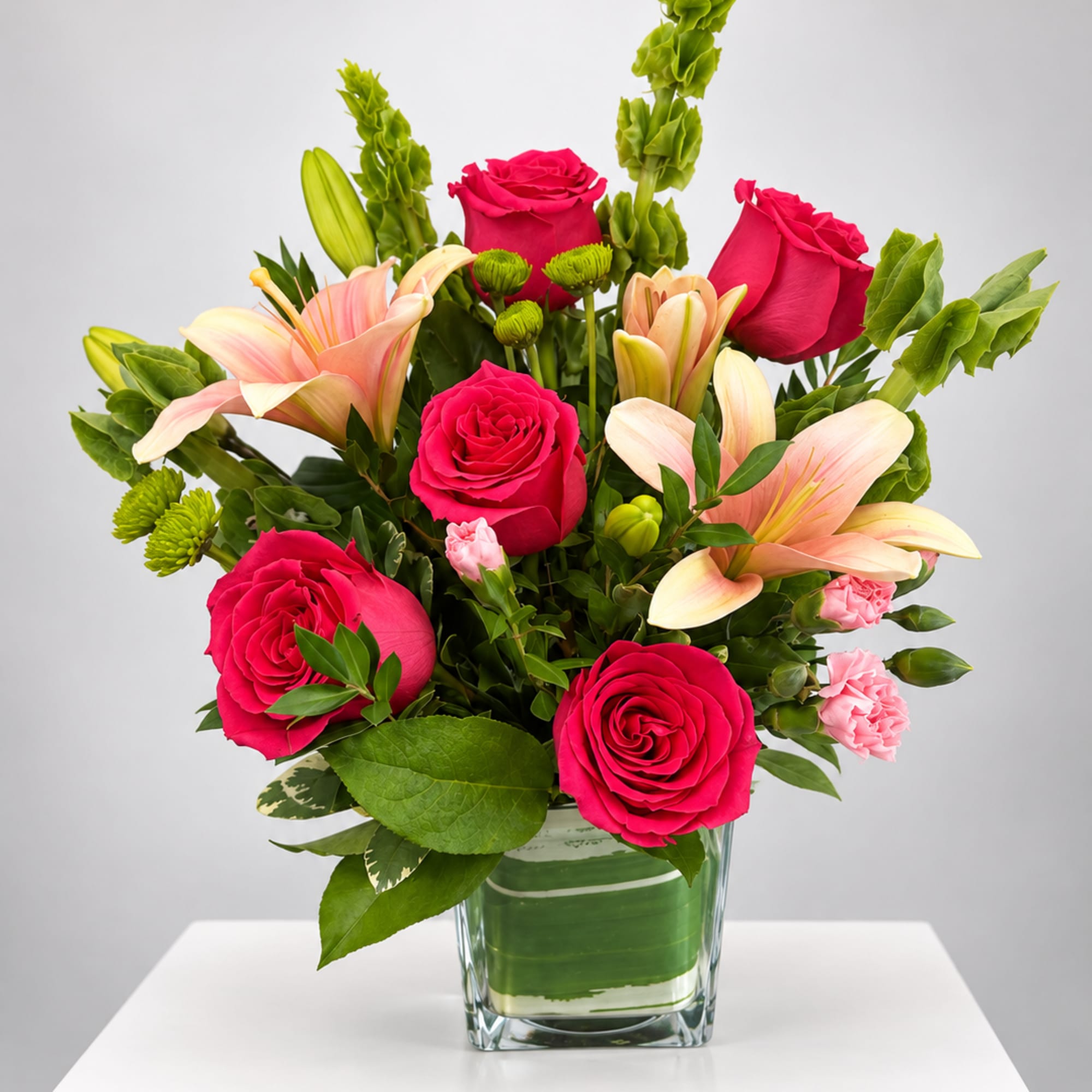 Pink roses and lilies arranged in a clear glass vase