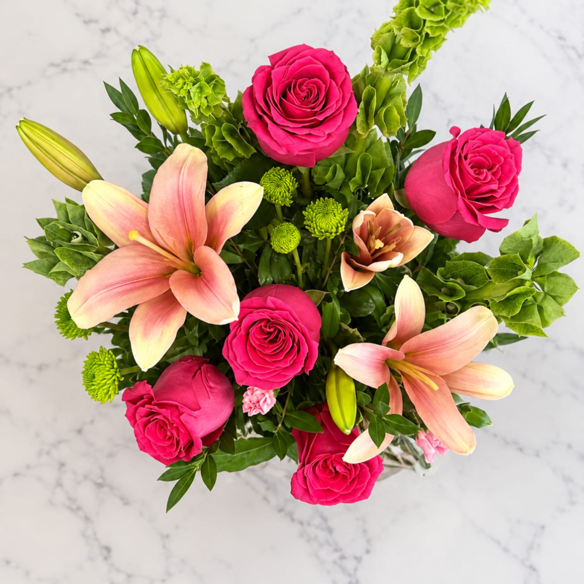 Pink roses and peach lilies arranged with green accents on a light background