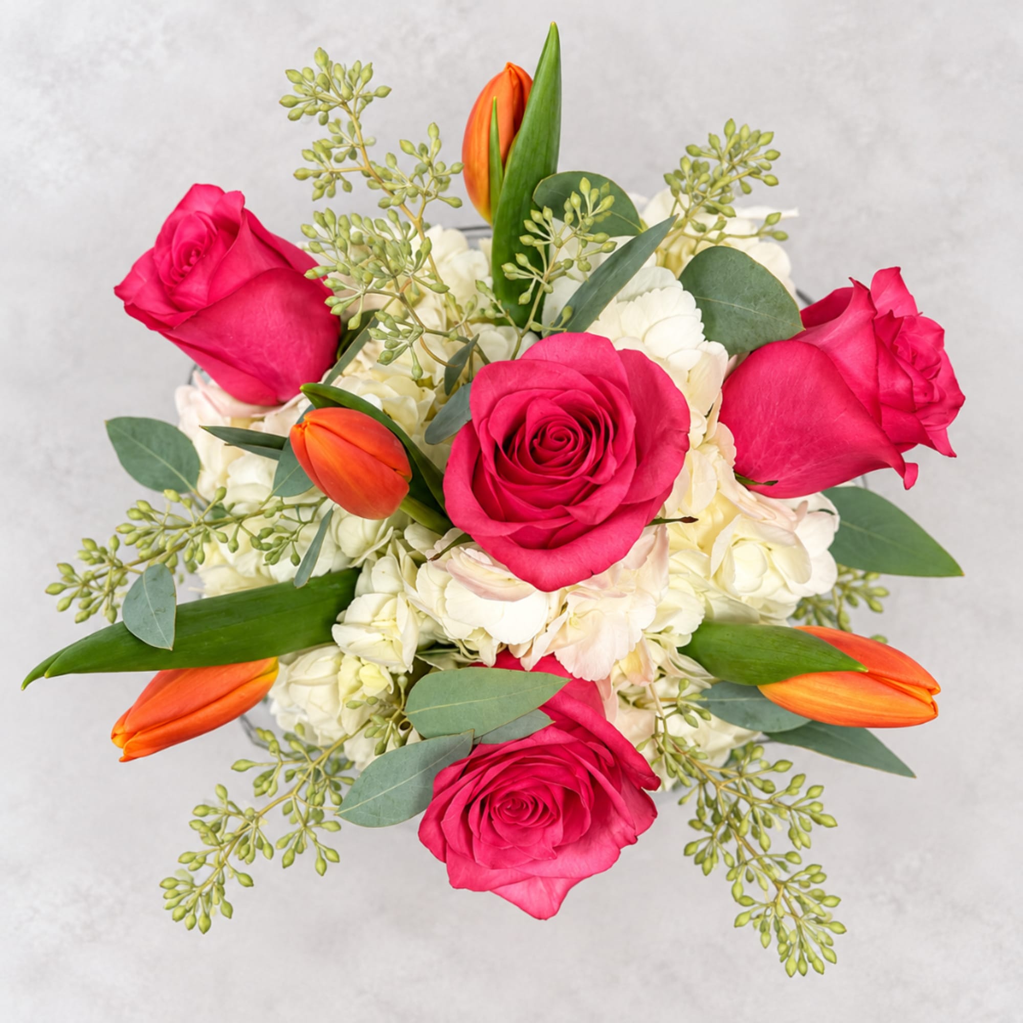 Pink roses and orange tulips in a white bouquet