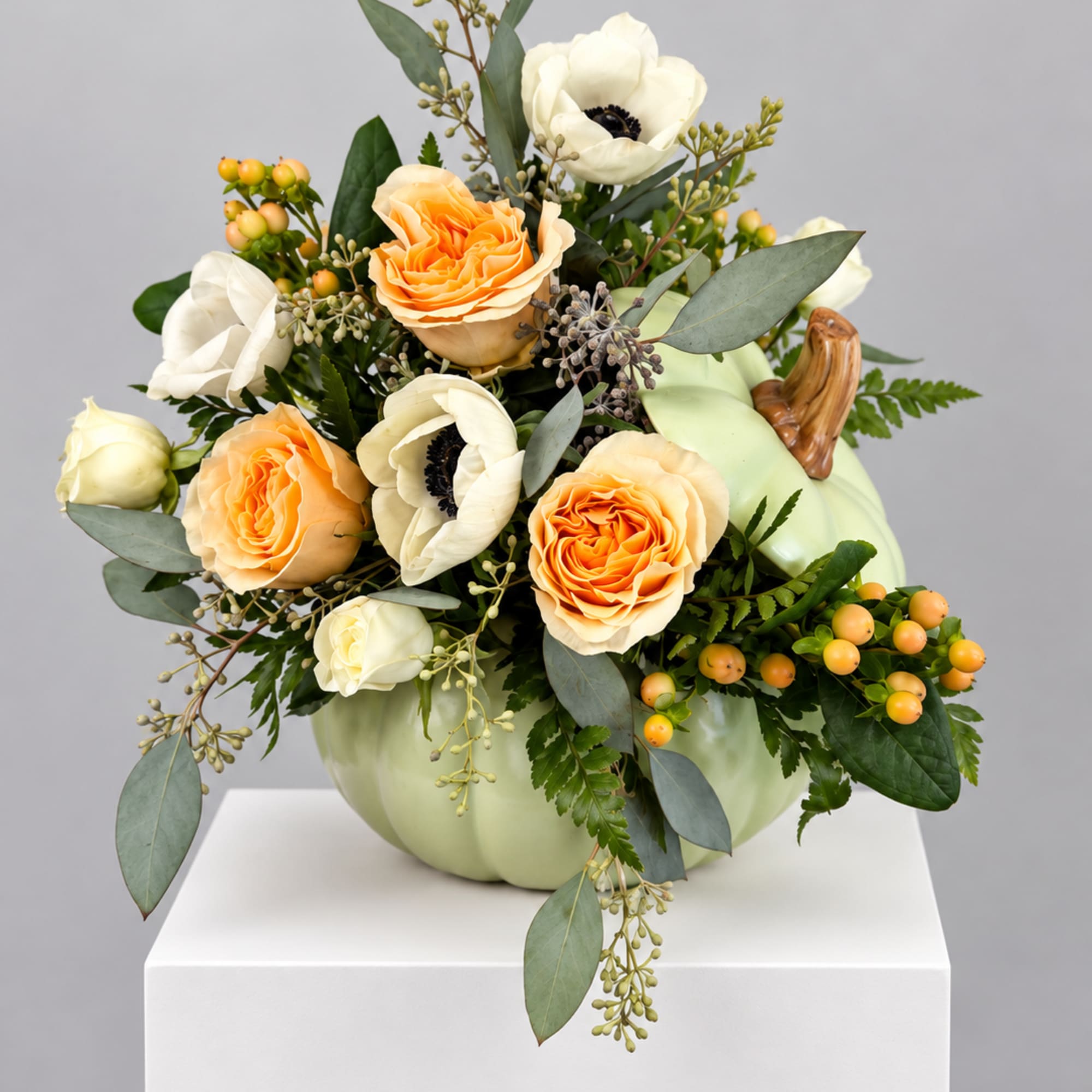Pumpkin-shaped vase with peach and white flowers and greenery